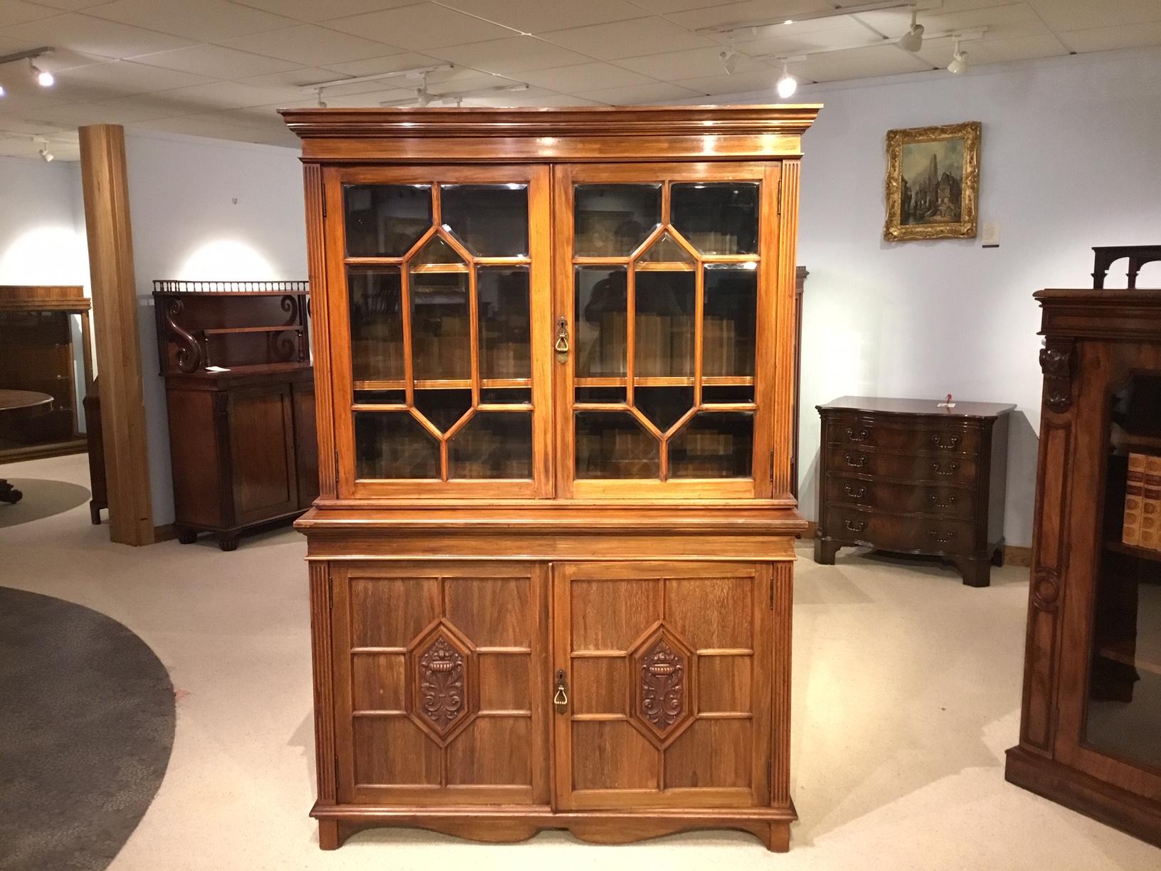 A good quality walnut Edwardian bookcase by Maple & Co. of London. The upper section with beveled glazed doors, which open to reveal two adjustable shelves flanked by reeded pilasters. The lower section has a solid walnut top above twin paneled