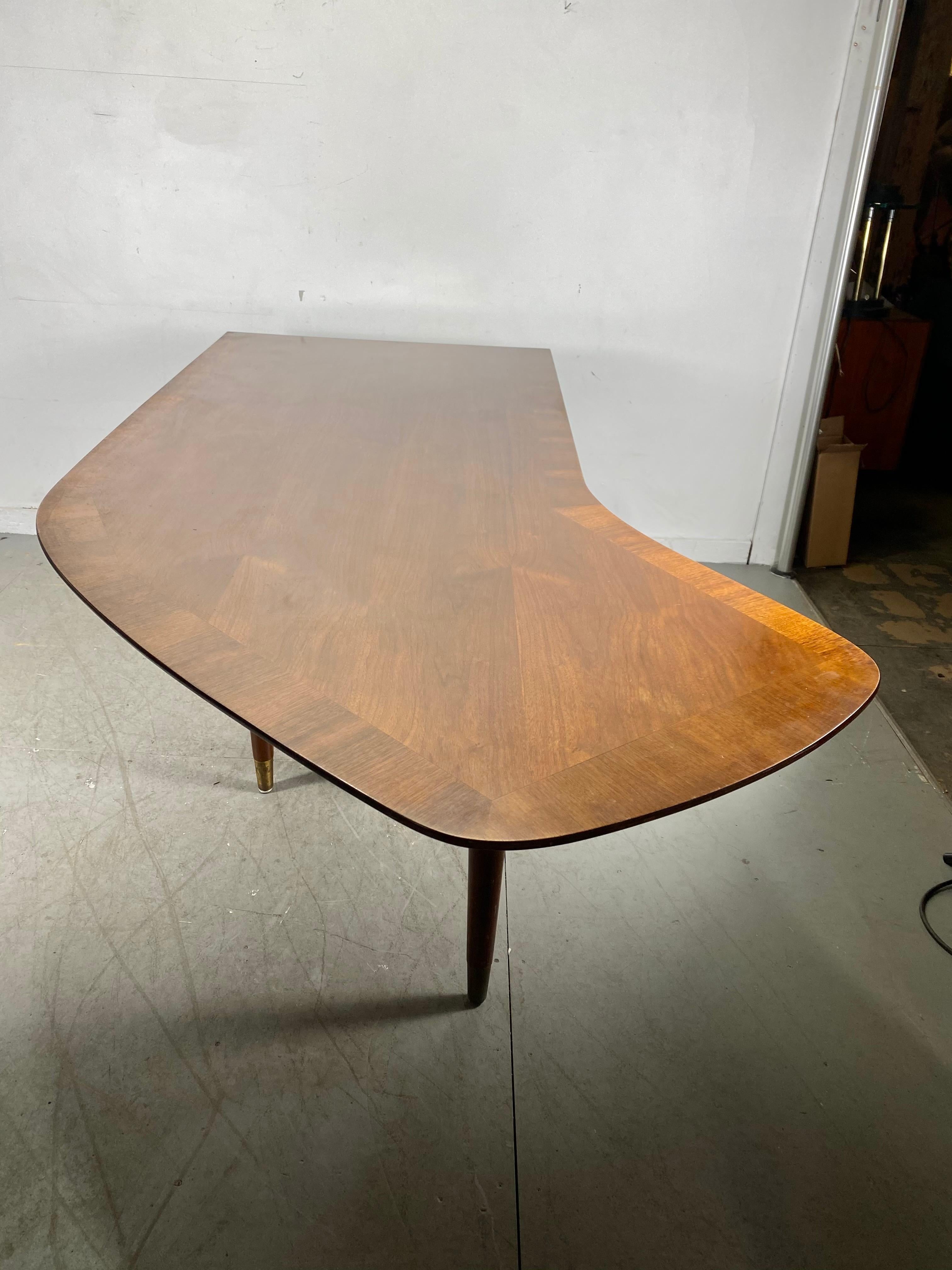 Classic modernist design !This walnut executive desk features a unique boomerang-shaped left return. The table surface is walnut and is edged with a band of contrasting grain wood. file drawer.. pull out writing surface,, Hand delivery avail to New