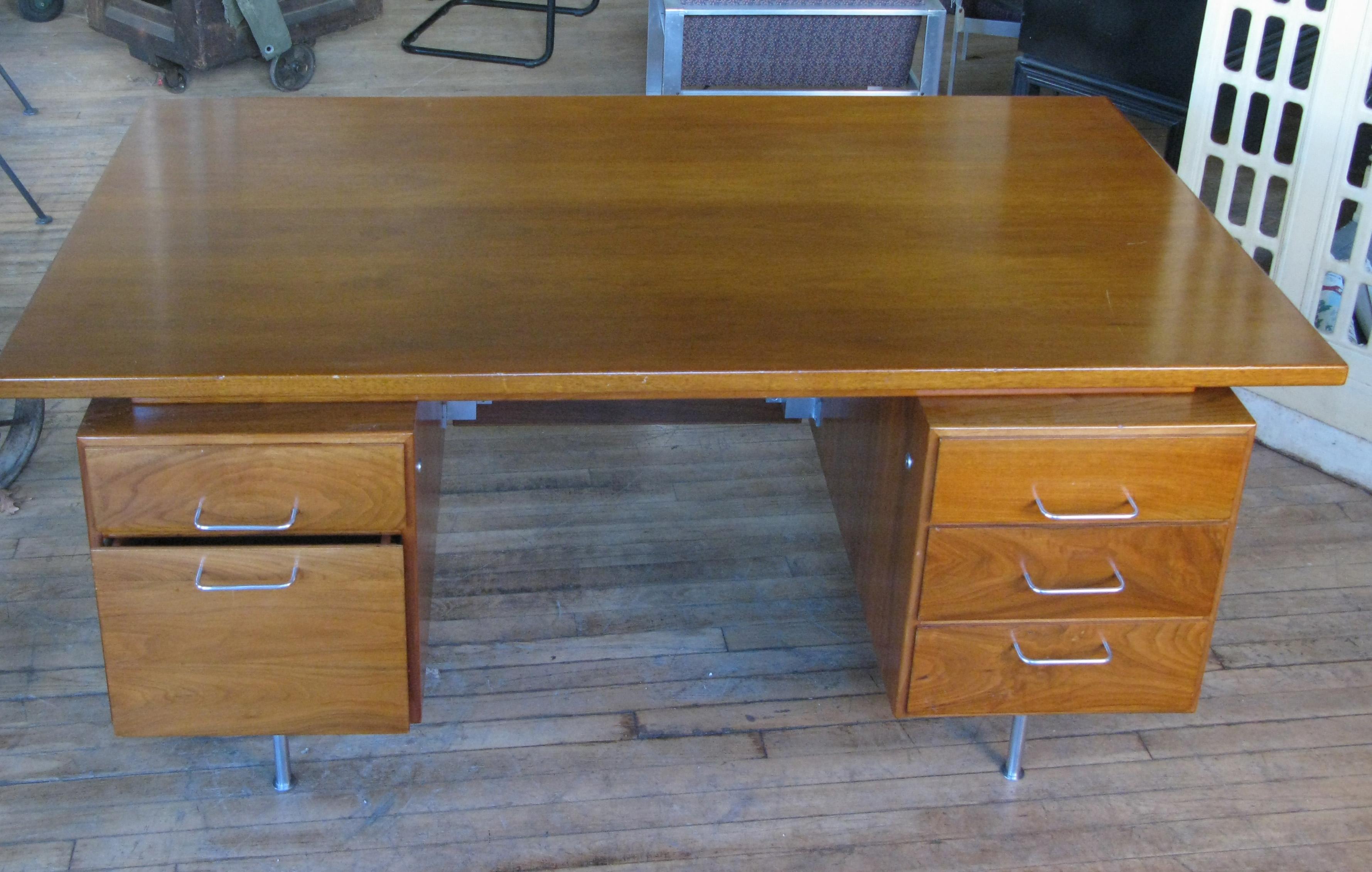 A very handsome vintage 1950s walnut executive desk designed by Jens Risom. Beautiful design with the case raised on steel legs, and with aluminum drawer pulls. This desk has the original walnut privacy screen. The drawers all have removable
