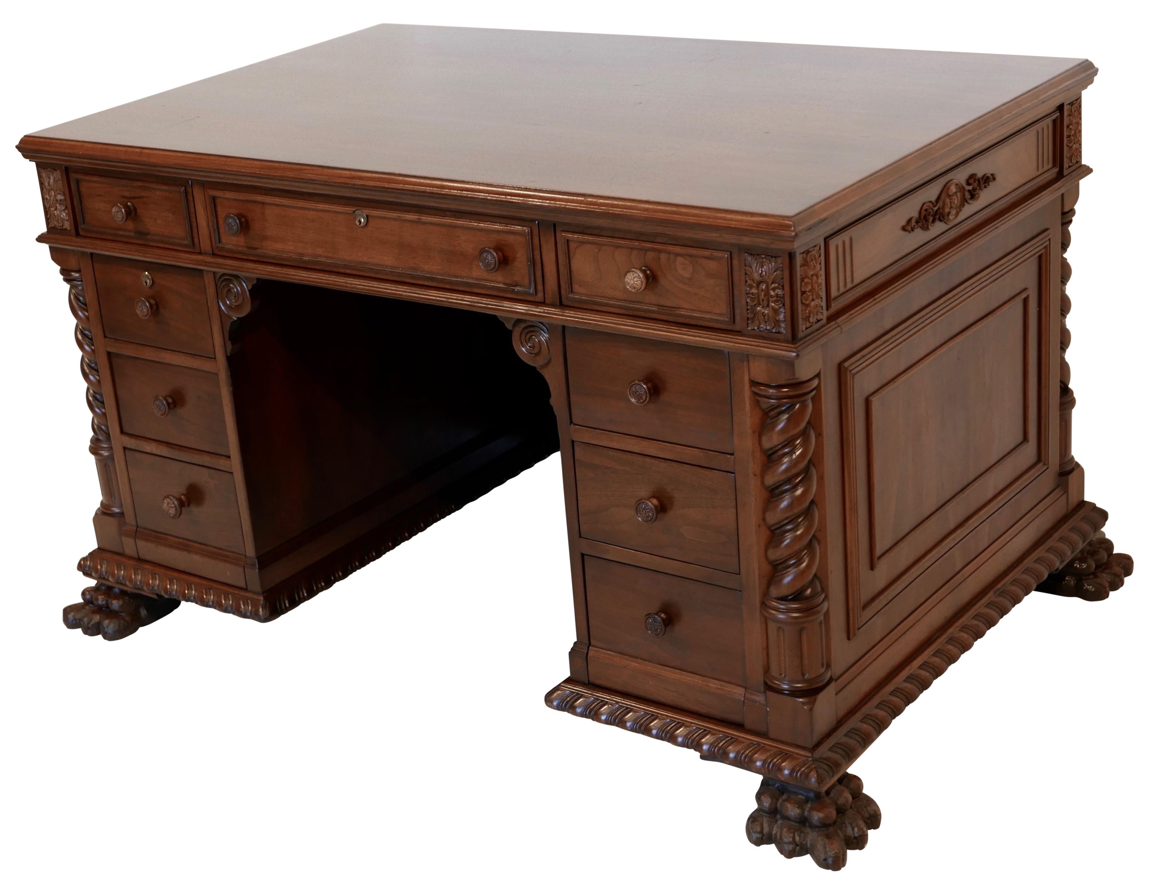 Unique executive walnut desk with decorative corner spiral columns, moulded panels on three sides, gadrooned base above four large lion paw feet. Locking center drawer flanked by four stacking drawers on either side, one drawer on the left side