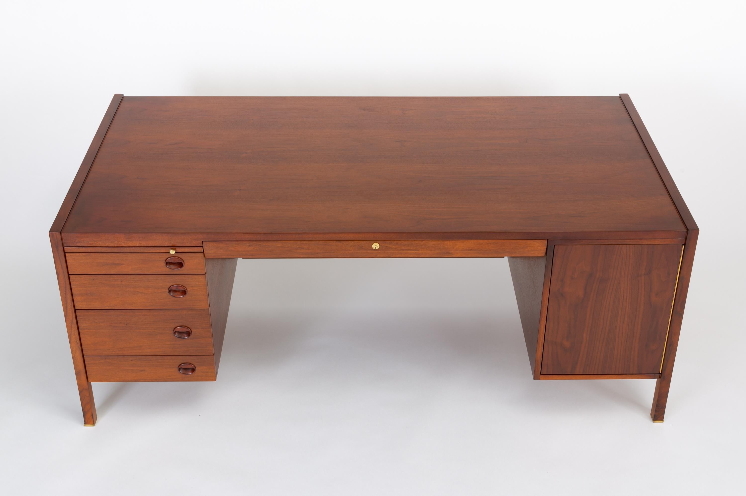 Edward Wormley’s stately Model 807 executive desk for Dunbar Furniture in walnut, with rosewood and brass details. The office Dunbar executive desk was a highly customizable design with four post legs and an inset modesty panel suspended between