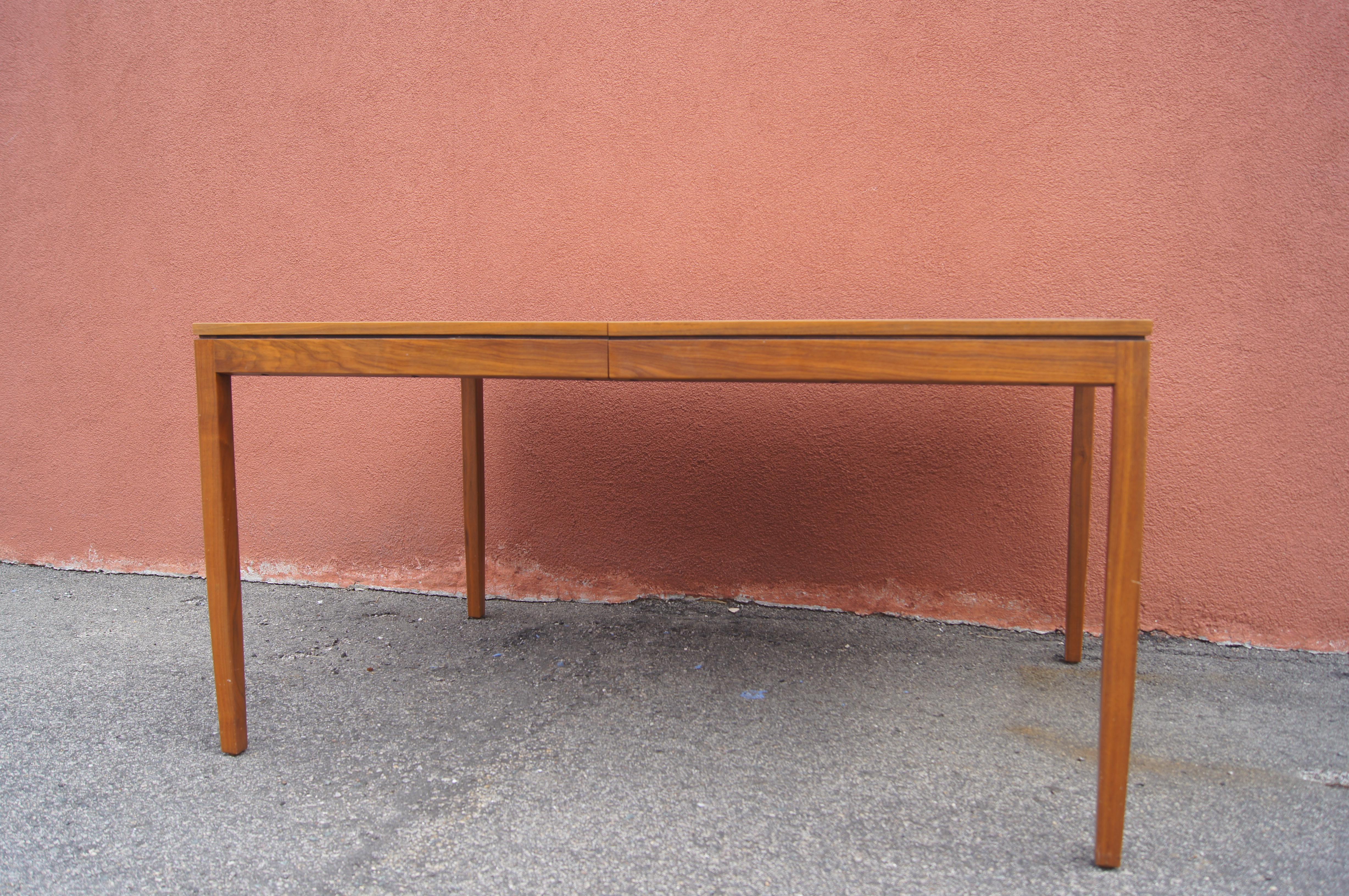 Florence Knoll designed this elegantly clean-lined table, model 303, for Knoll associates. It is composed of a warm walnut. A 28-inch center leaf, which stores within the table, extends the surface to 84 inches, seating ten.