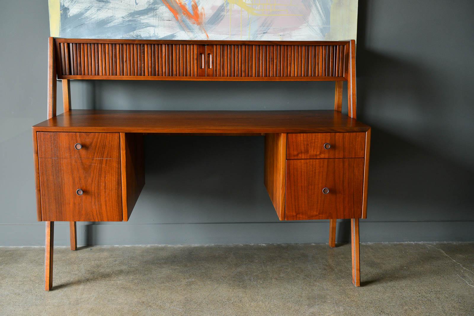 Walnut floating top tambour door desk, circa 1969. Professionally restored in showroom condition with original white upper shelf dividers. Gorgeous walnut grain and floating leg design. Finished on the reverse so it can be floated in the middle of