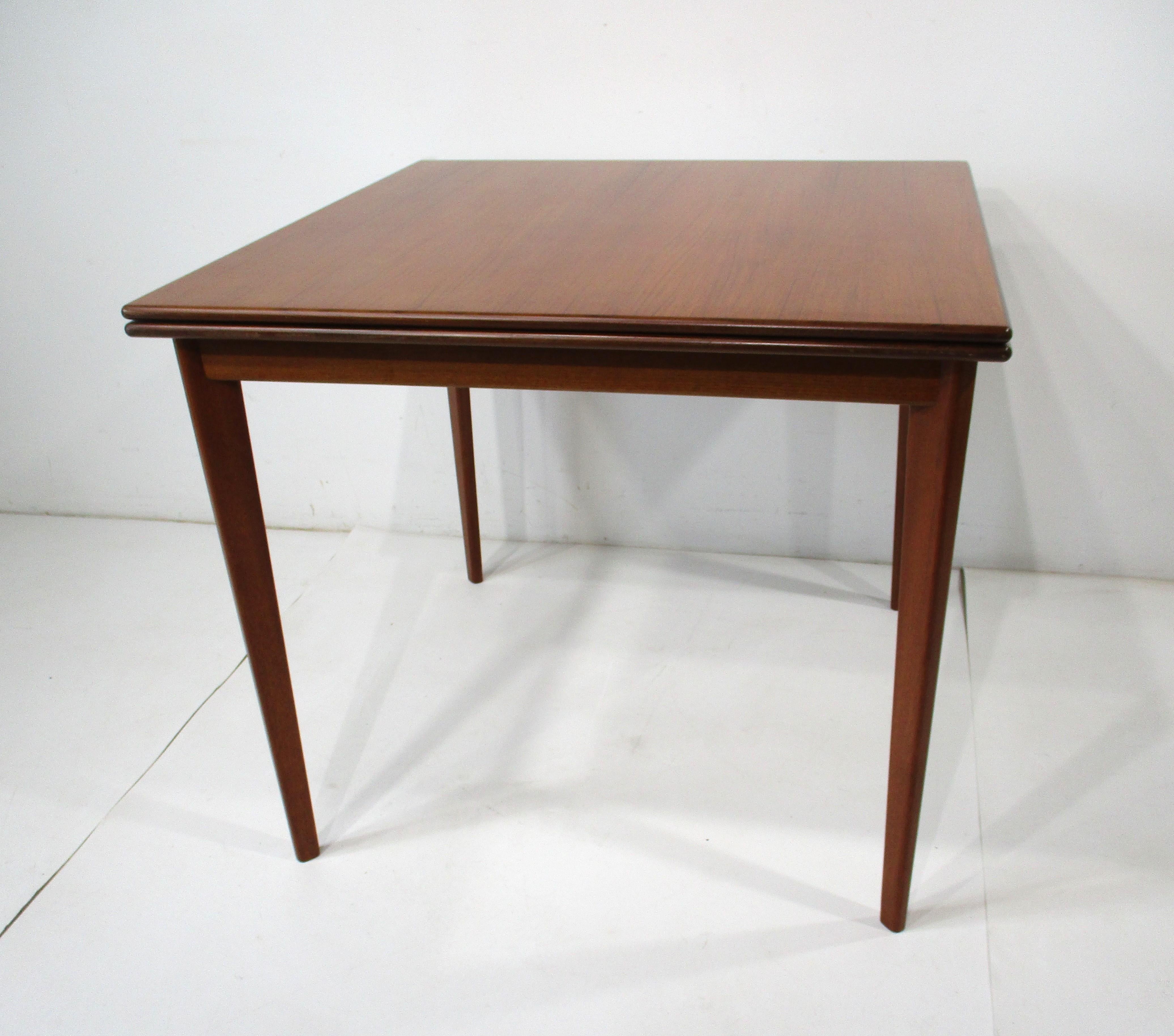 A very well crafted folding dining room or game table in a nicely grained walnut with a darker walnut bull nosed edge . The contrasting wood detail presents splendidly mixed with the brass hinges giving the table a clean sophisticated look and feel