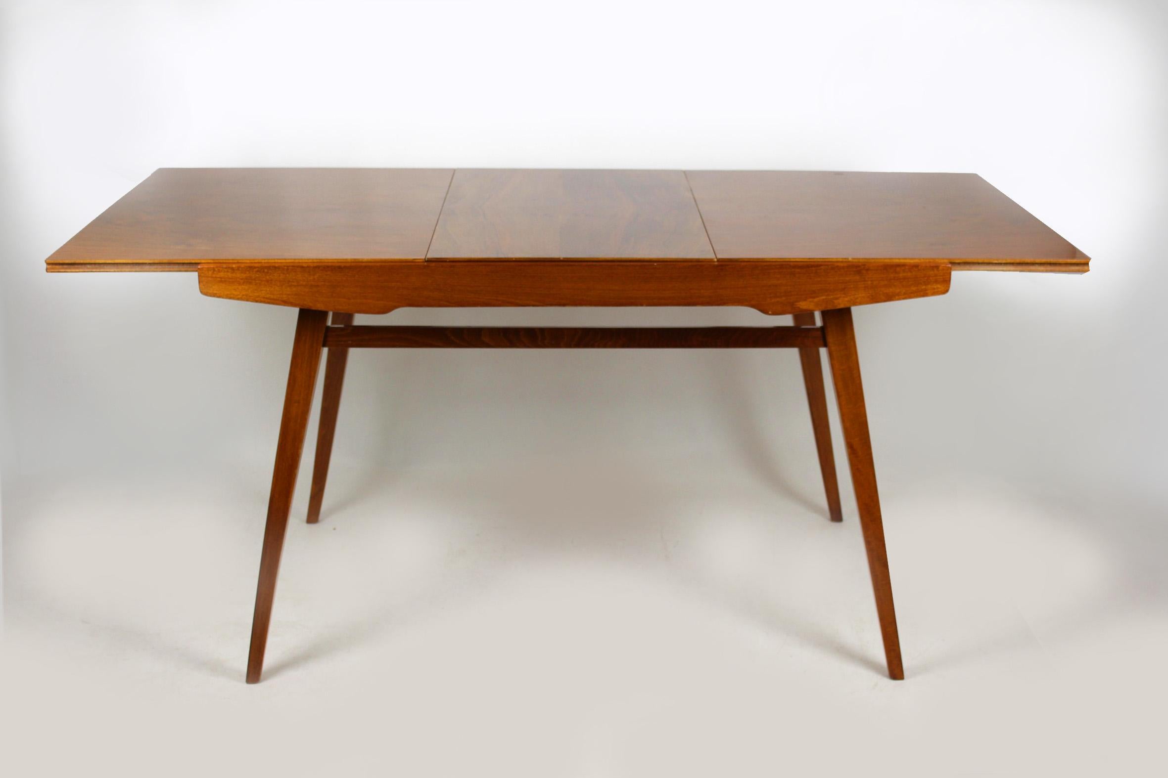This walnut veneered folding dining table was manufactured by Tatra in the 1960s. The table measures 165cm wide when fully extended.