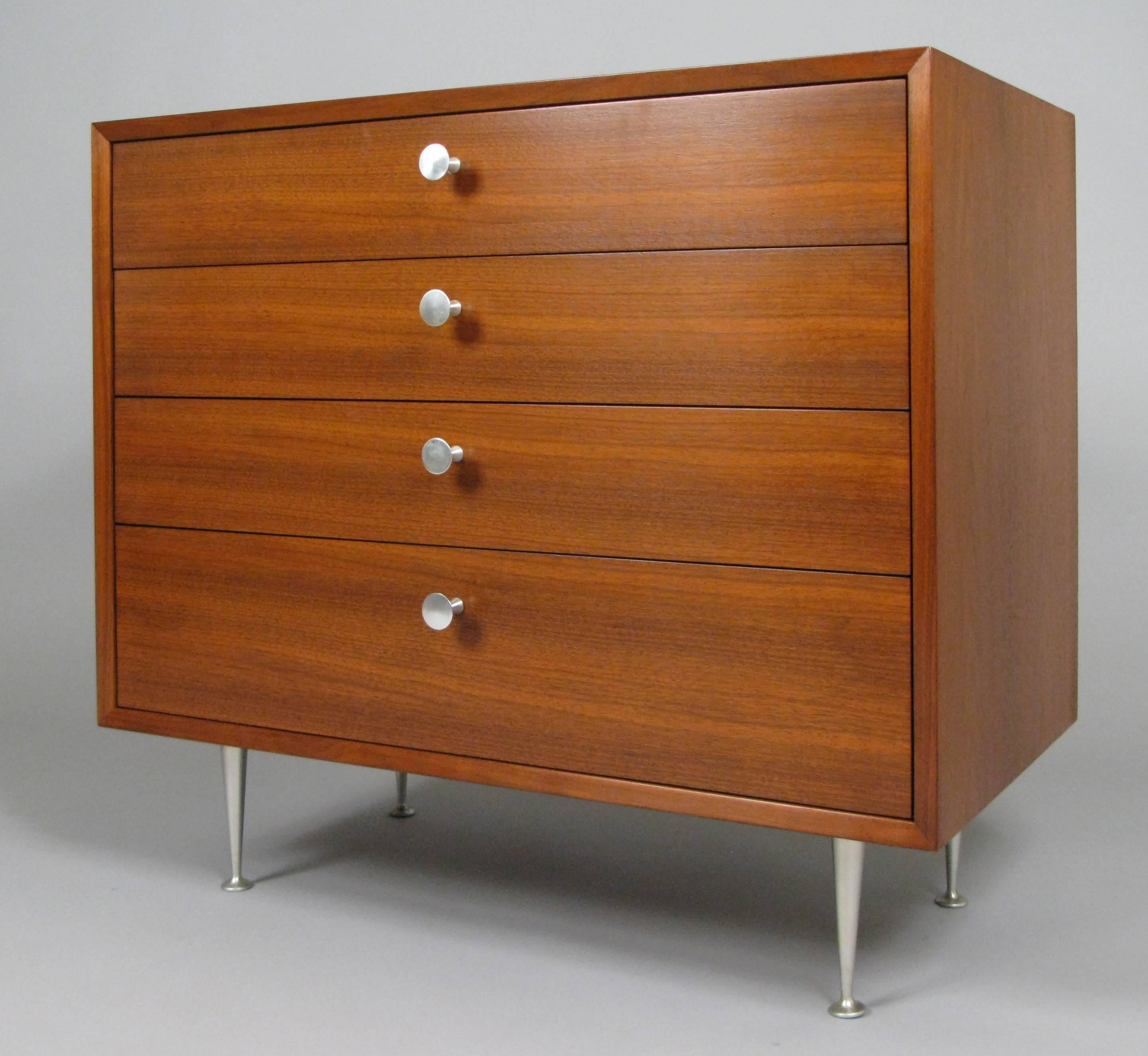 A very handsome walnut four-drawer chest with aluminum legs and pulls designed by George Nelson for Herman Miller, circa 1950. Beautiful scale and details. Two of the drawers are divided and the top drawer has a hinged mirror, which can easily be