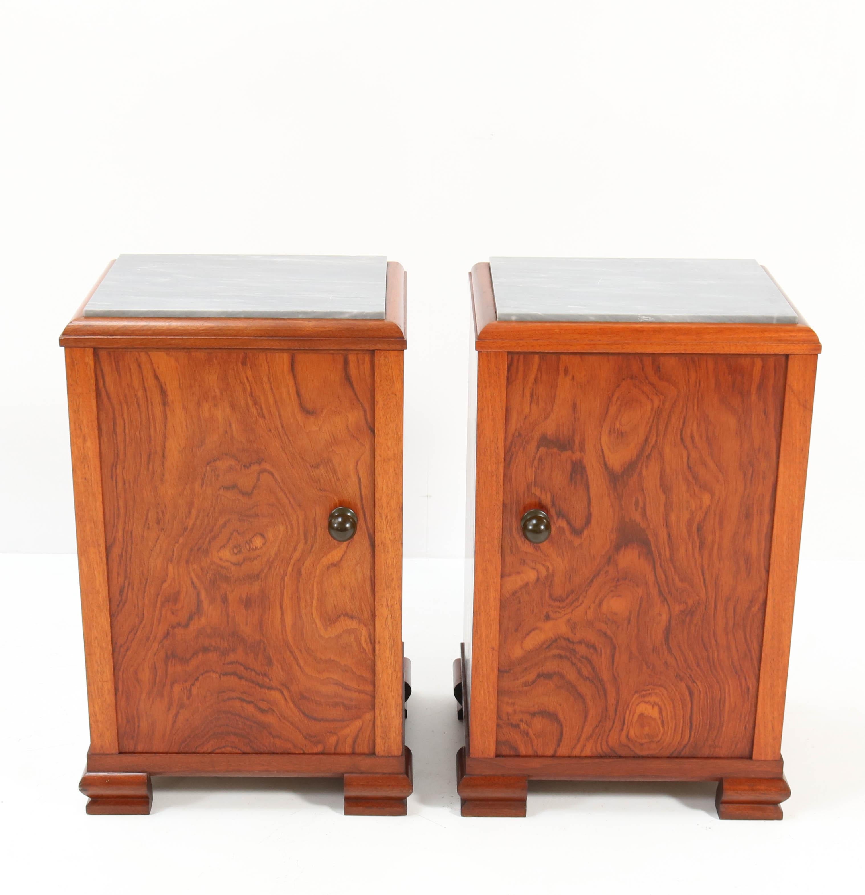 Wonderful pair of Art Deco nightstands or bedside tables.
Striking French design from the 1930s.
Solid walnut and walnut veneer with original patinated brass knobs.
Original grey marble tops.
In very good condition with a beautiful patina.
