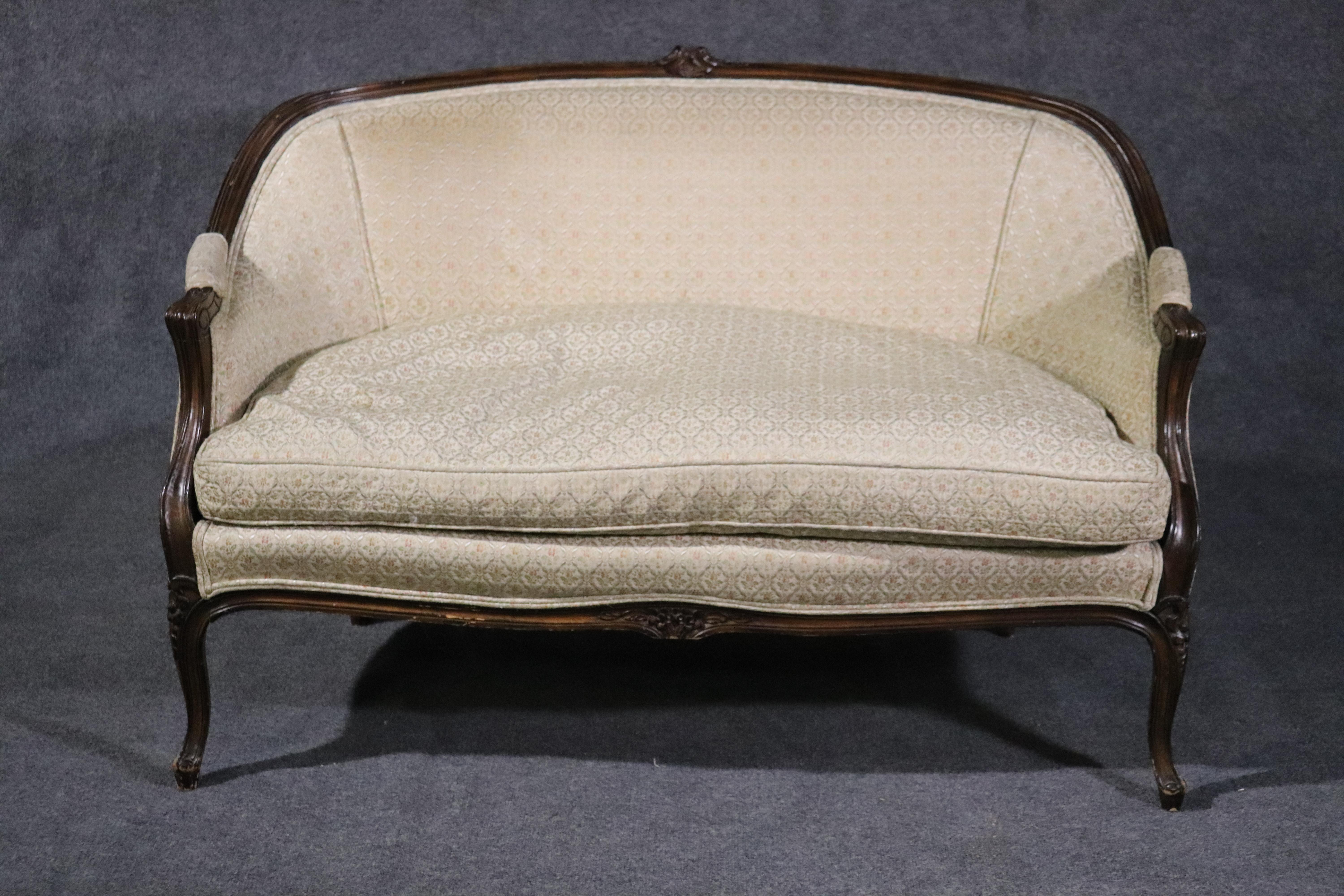 This is a nice little French Louis XV style walnut canapé. Made in the USA, this one has a nice and very comfortable goose feather filled cushion. The upholstery is used and 70 years old so expect some issues, but its frame is very nice. The settee