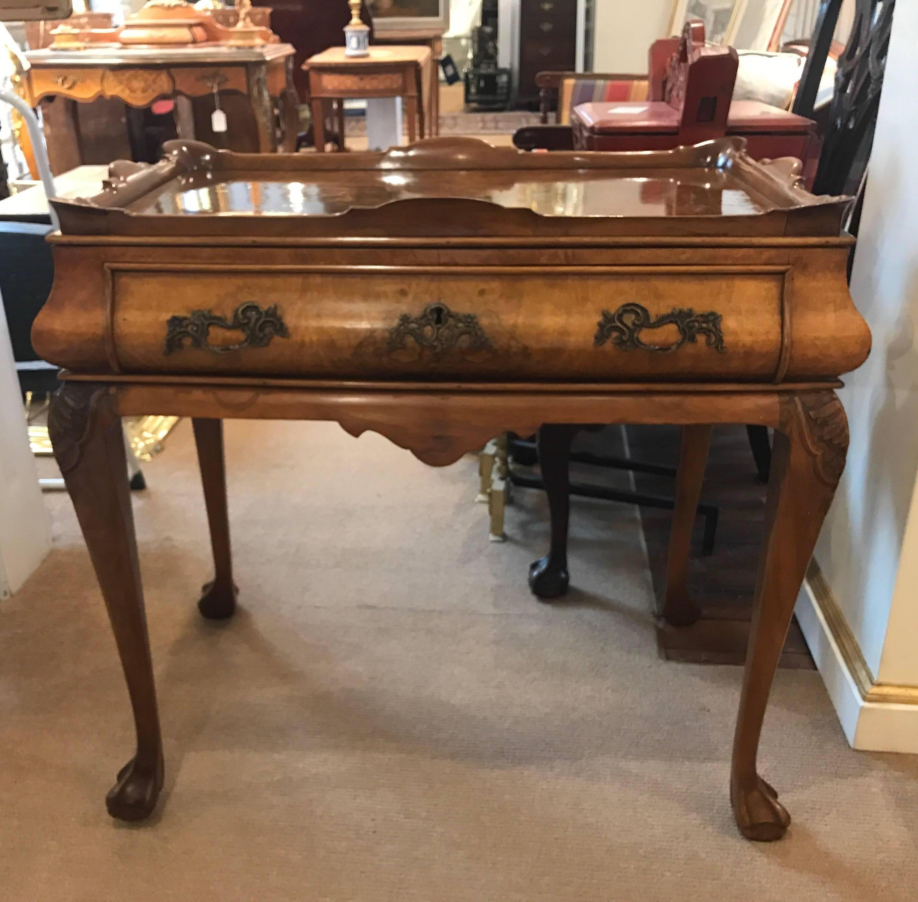 A walnut tea table with gallery top. The figurative walnut grained top over single centre drawer resting on four cabriole legs with carved detail on the knees. The finish is recently French polished showing a well cared for aged finish.