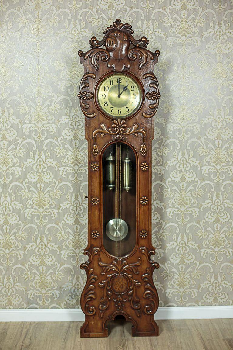 The wooden case of the clock is made in solid walnut wood.
The sides have a relief. The front is ornamented with a semi-plastic woodcarving decoration with floral motifs.
The clock strikes every full and half hour.
The inside can be accessed by