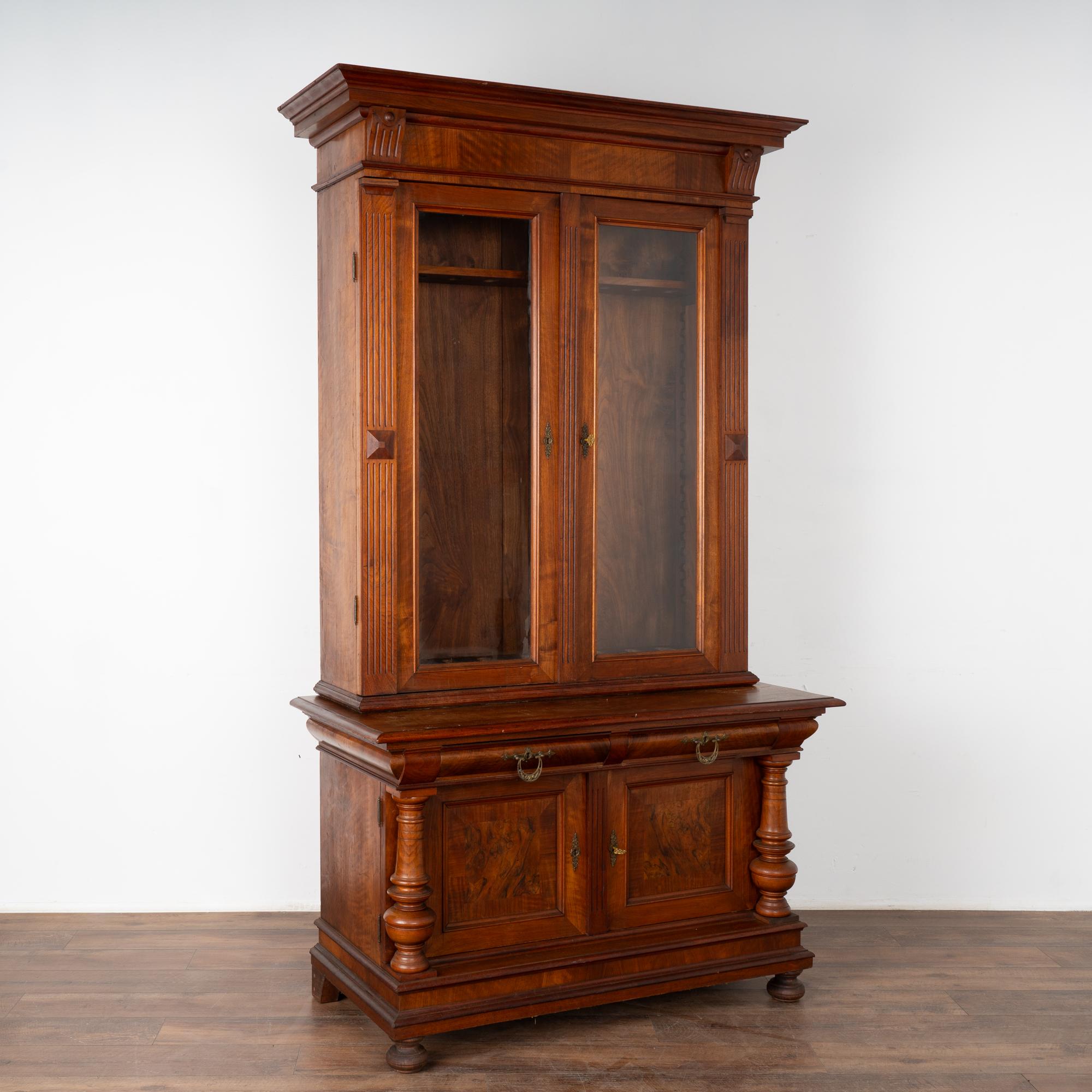 Striking walnut gun cabinet with attractive fluted carving and turned columns. Holds 9 guns and stands 7.5' tall.
Lower cabinet has two drawers over two doors, which open to reveal 4 interior central drawers.
Locks no longer function. 2 keys