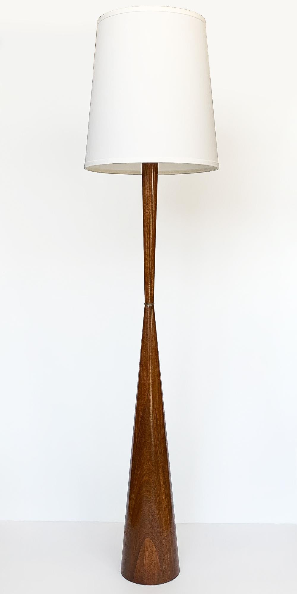 Solid walnut hourglass shaped floor lamp in the style of Raymond Pfenning and Phillip Llyod Powell, circa 1970s. Hand-turned solid walnut floor lamps with brass insert on neck. Brass socket, harp and ball finial. Takes one standard base light bulb.