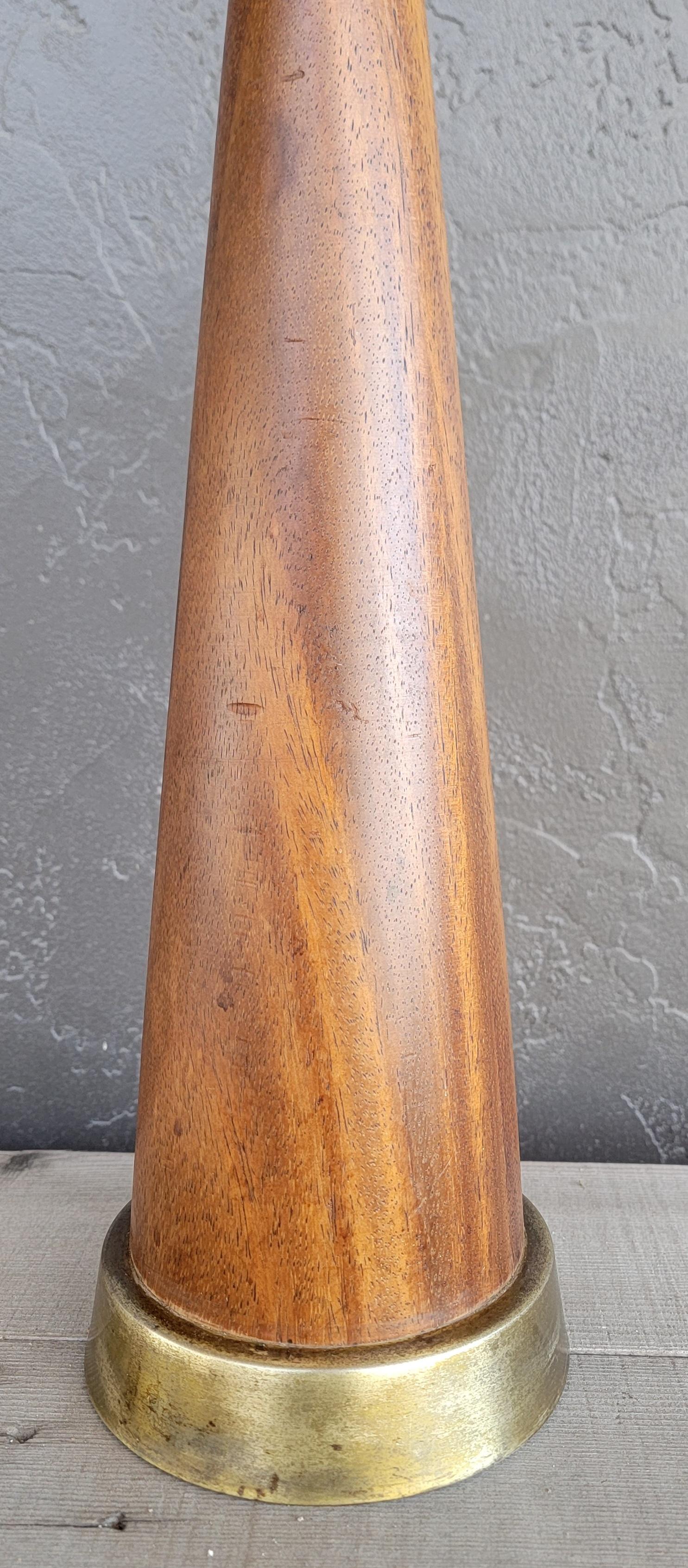 Turned walnut hourglass table lamp in the manner of Phillip Lloyd Powell. Circa. 1960. Beautifully grained walnut with nice glow to original finish. Brass base has some tarnishing. Offered without lamp shade.

45 inches high. (base to finial)
6.5