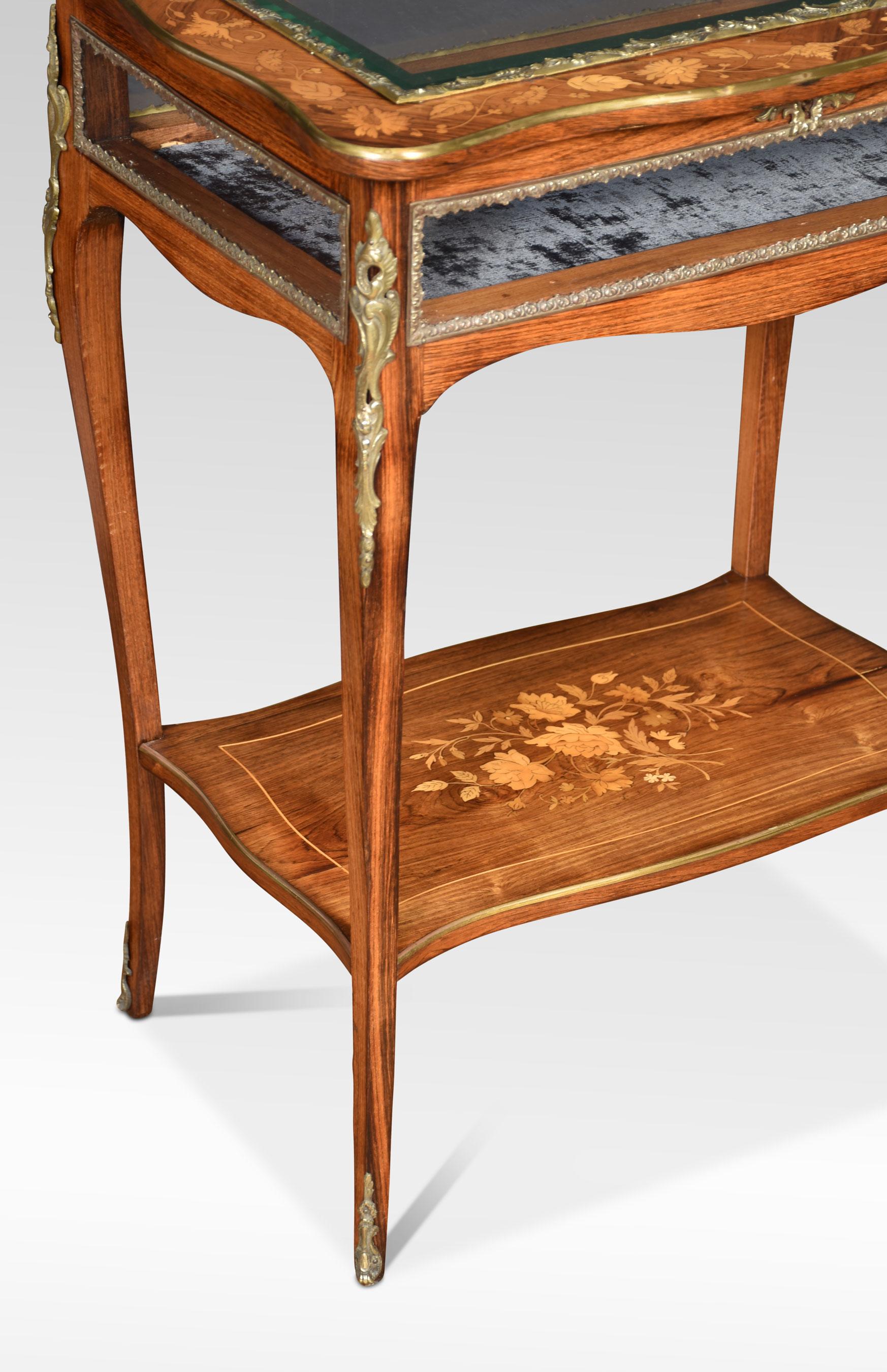 Walnut inlaid and metal mounted bijouterie tables, the top with beaded edge inset with a beveled glass panel and with beveled glass sides, enclosing a velvet-lined well. Over a shaped apron, on slender cabriole legs with brass mounts and sabots.