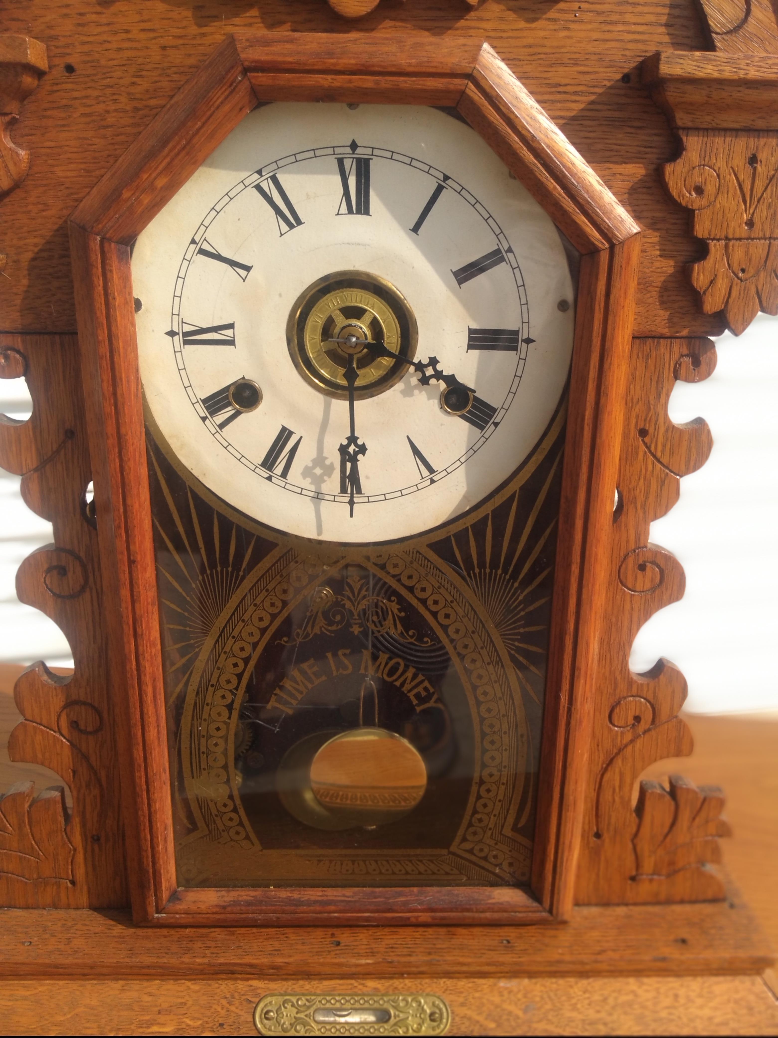 This is a late 19th century gingerbread mantle clock. The clock is from the Eastlake period. The face of the clock is white porcelain. The clock is nicely carved and has brass accents.