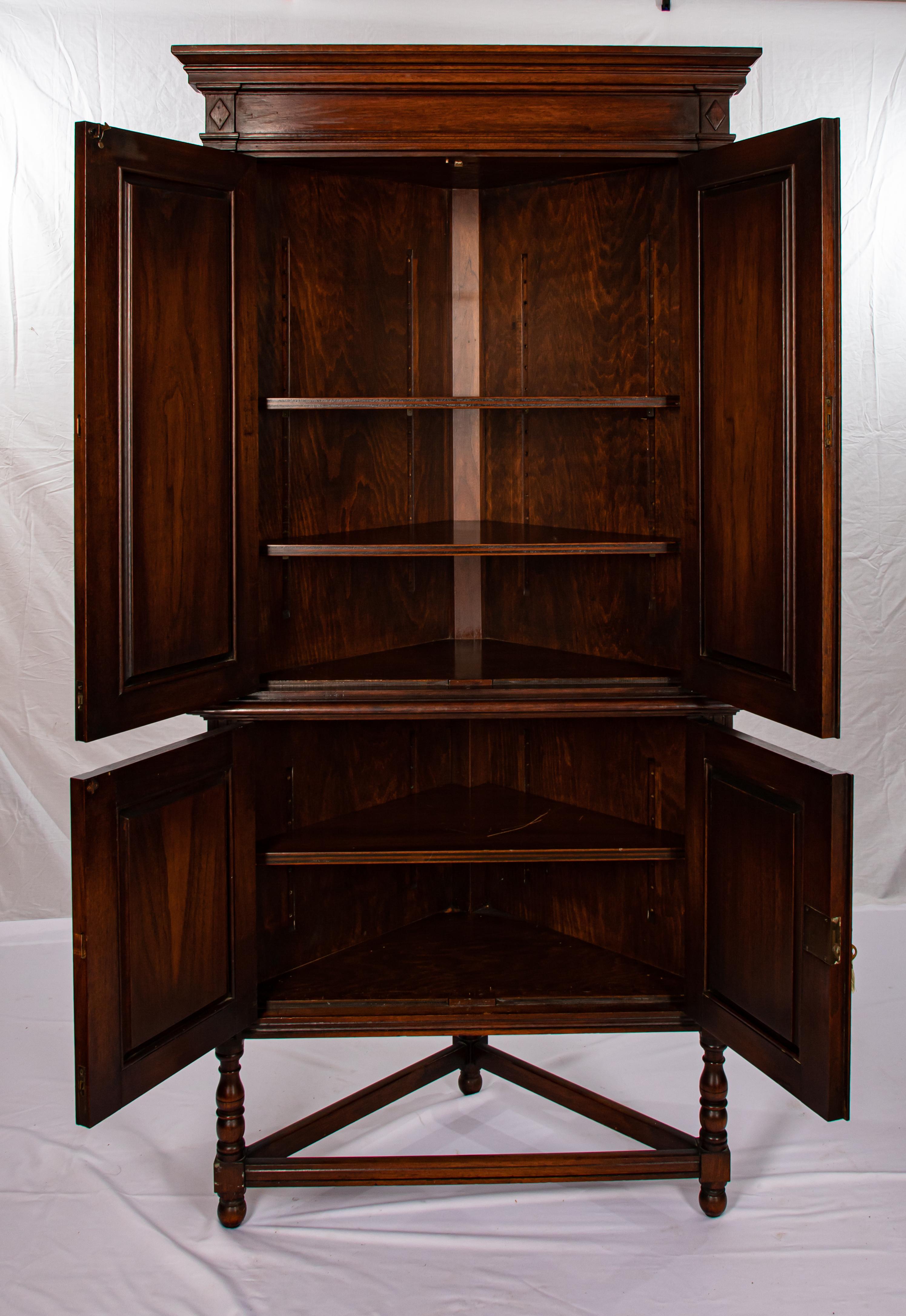 Offering this stunning walnut English corner cupboard. Starting on a simple base with stretchers. It rises from there to the bottom half of the cabinet with two doors that are lightly carved with a diamond that has a floral detail. From there is the