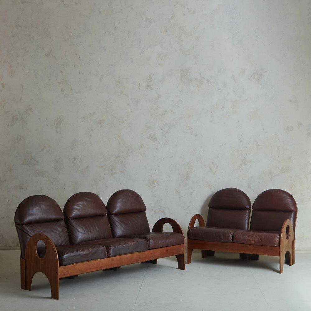 A three-seat ‘Arcata’ sofa designed by Gae Aulenti for Poltronova in 1968. This sculptural sofa features a walnut frame with an arched seat back and arms, whose curves are emphasized by circular and demilune cutout details. This sofas retains its