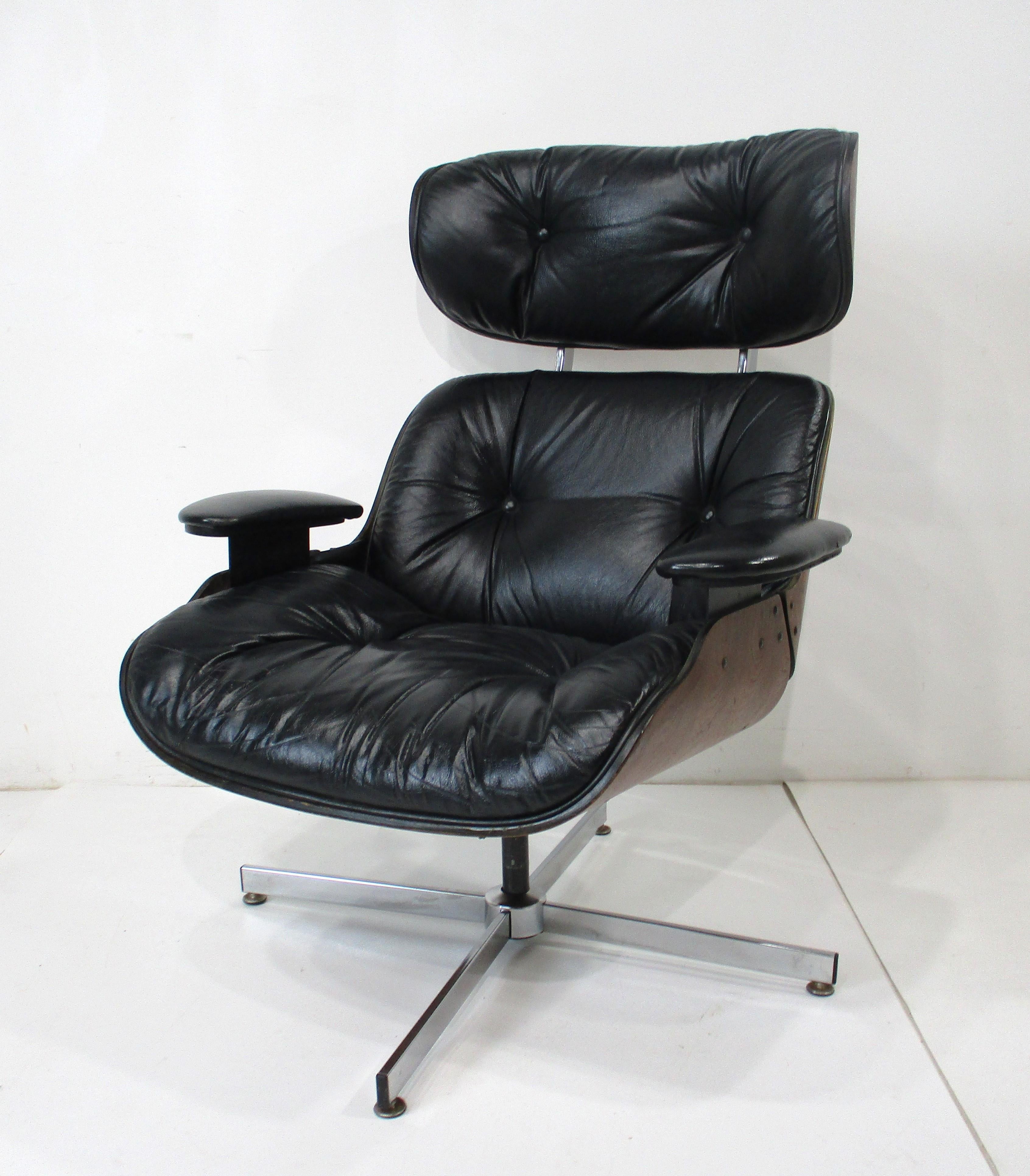 A bent wood walnut Mid Century lounge chair with black leather seat sitting on a chrome base . Unlike the classic Eames lounge chair this model has a spring base for movement which for some people is a more comfortable and  it also swivels ,
