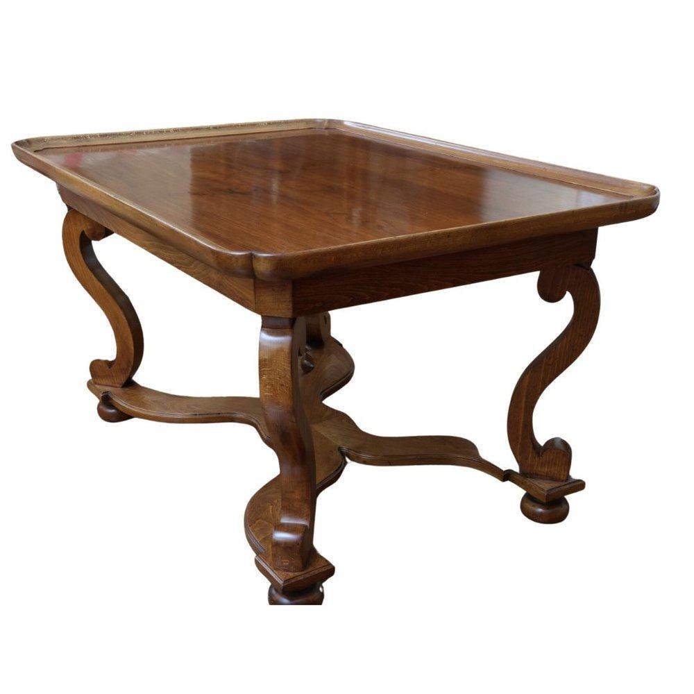 Table de bibliothèque en noyer avec des pieds en volutes et une traverse en X.  La table est dotée d'un rebord profilé et incurvé sur son pourtour, ce qui lui confère l'aspect d'un plateau.  Les magnifiques pieds en volutes et la base en X incurvée