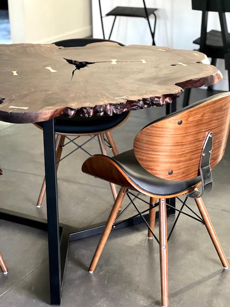 Heirloom quality, this dining table is handmade from a single slab of solid walnut and features a beautiful grain. 
Contrasting Maple bowtie inlays are arranged down the center cracks.
The natural void in the center is left open. 

Handcrafted