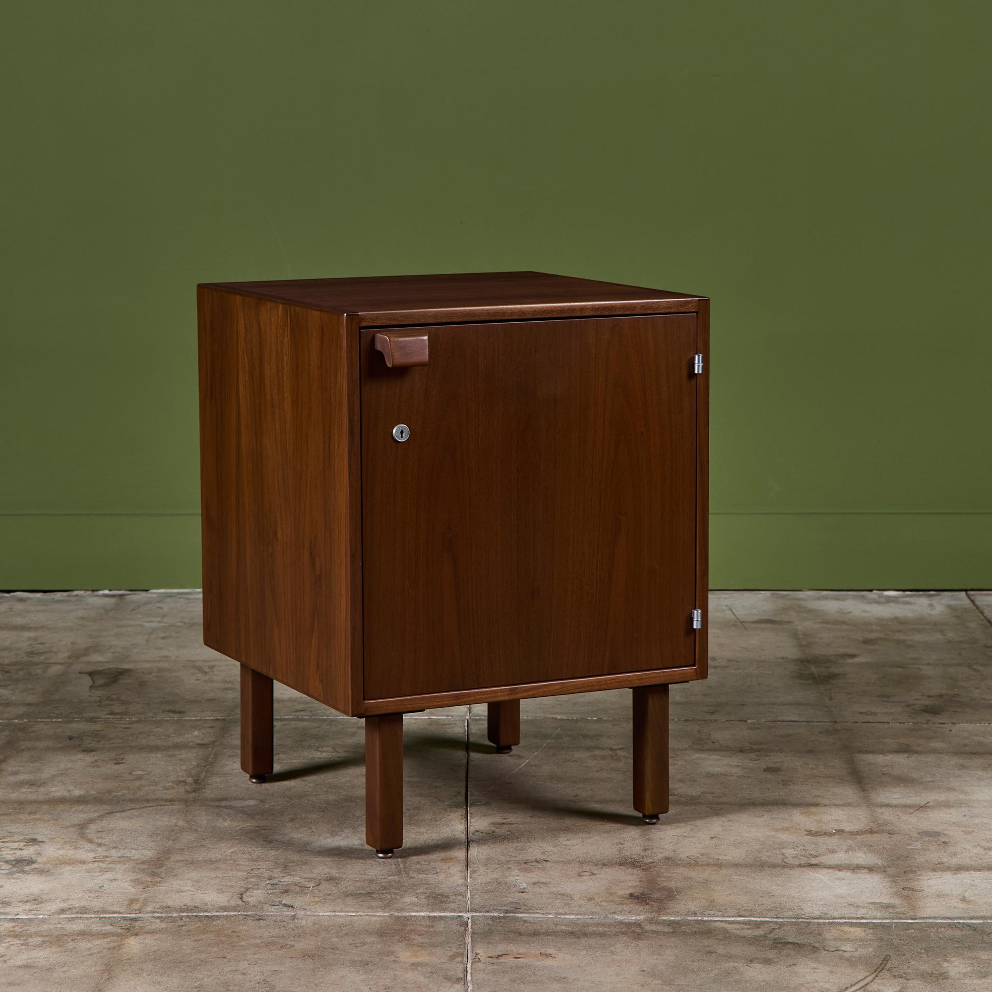 Designed by Jens Risom, USA, c.1960s. This walnut cabinet features a single compartment with a hinged door and an interior adjustable shelf. The cabinet rests on four wood legs with metal capped feet.  Jens Risom Design Label are