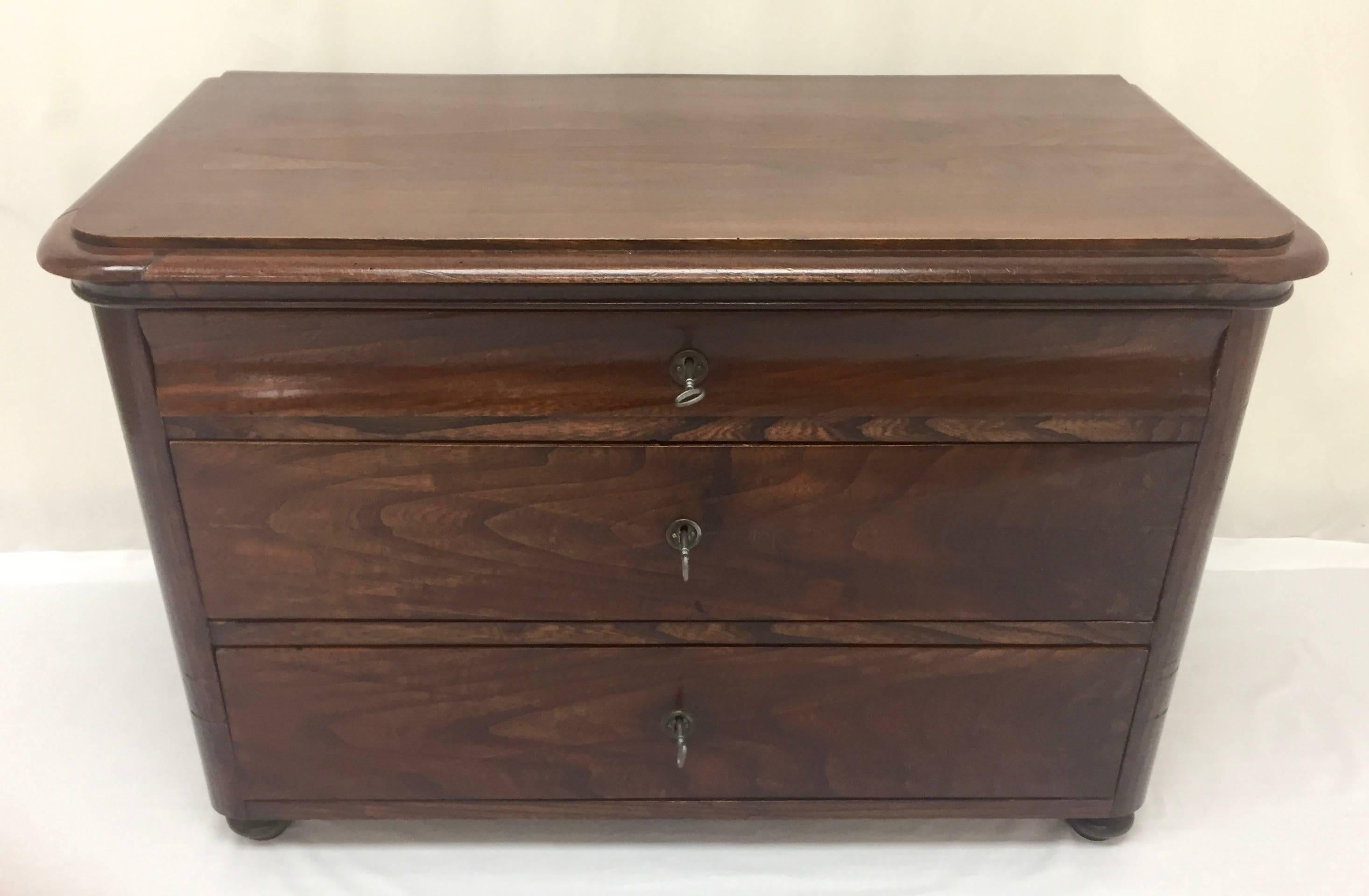 This handsome little French chest of drawers or commode is made of book-matched walnut using yellow pine as the secondary wood. The top drawer bears the typical curvature of the Louis-Philippe style but its interior has something special. At the