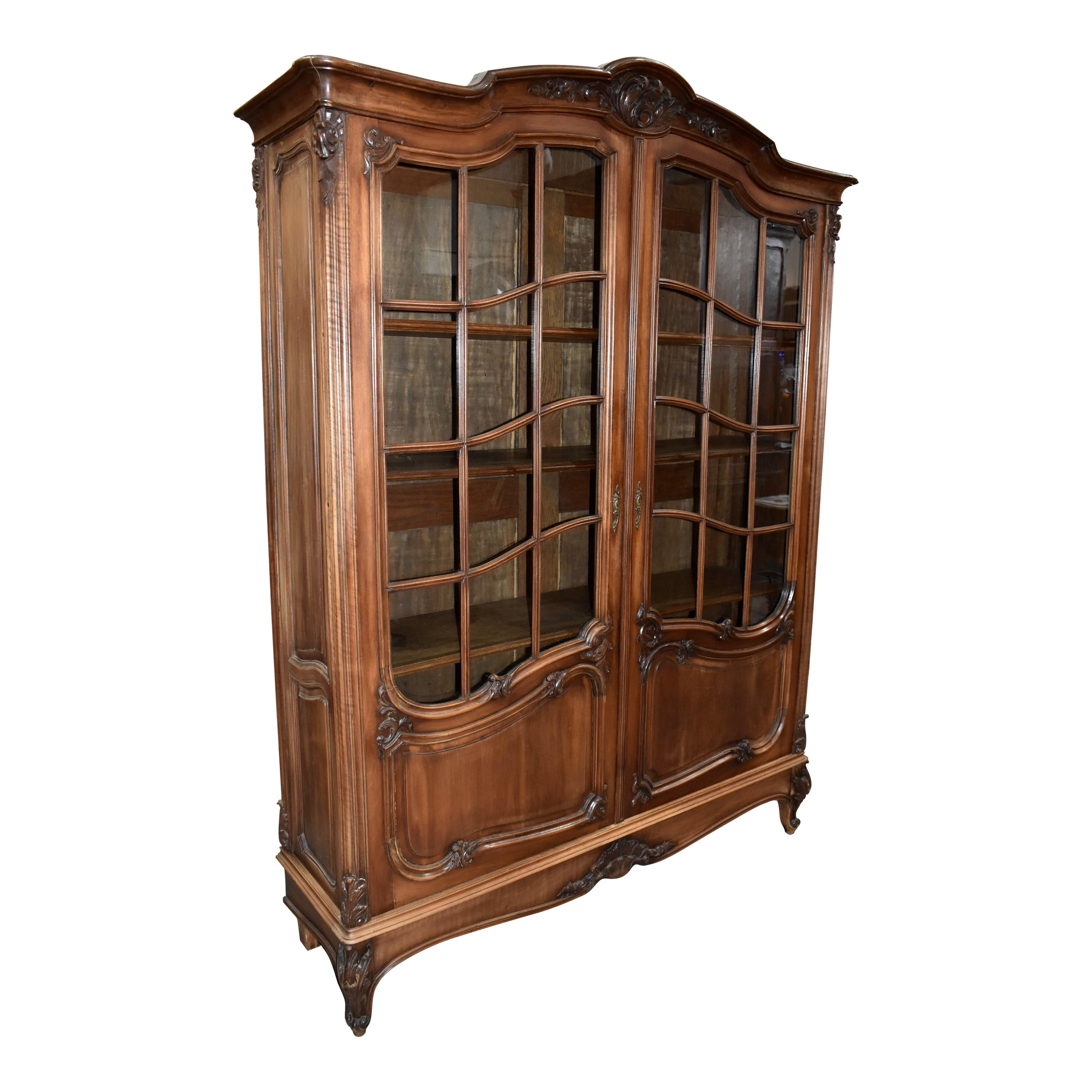 Elegant in every way, this late-19th century, Louis XV bookcase is as stunning as it is practical. The beautiful, tight grain of walnut, finished in a medium stain is showcased on the exterior. Inside, the bookcase is comprised of oak. The