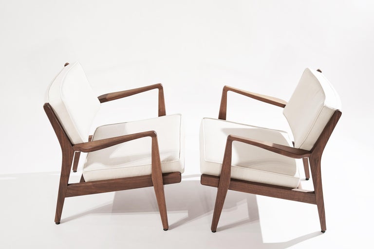 Mid-Century Modern Jens Risom lounge chairs expertly restored walnut frames and reupholstered twill by Holly Hunt. This ergonomically focused design places you in a balanced position upon seating in a way that relieves lower back and hip pressure