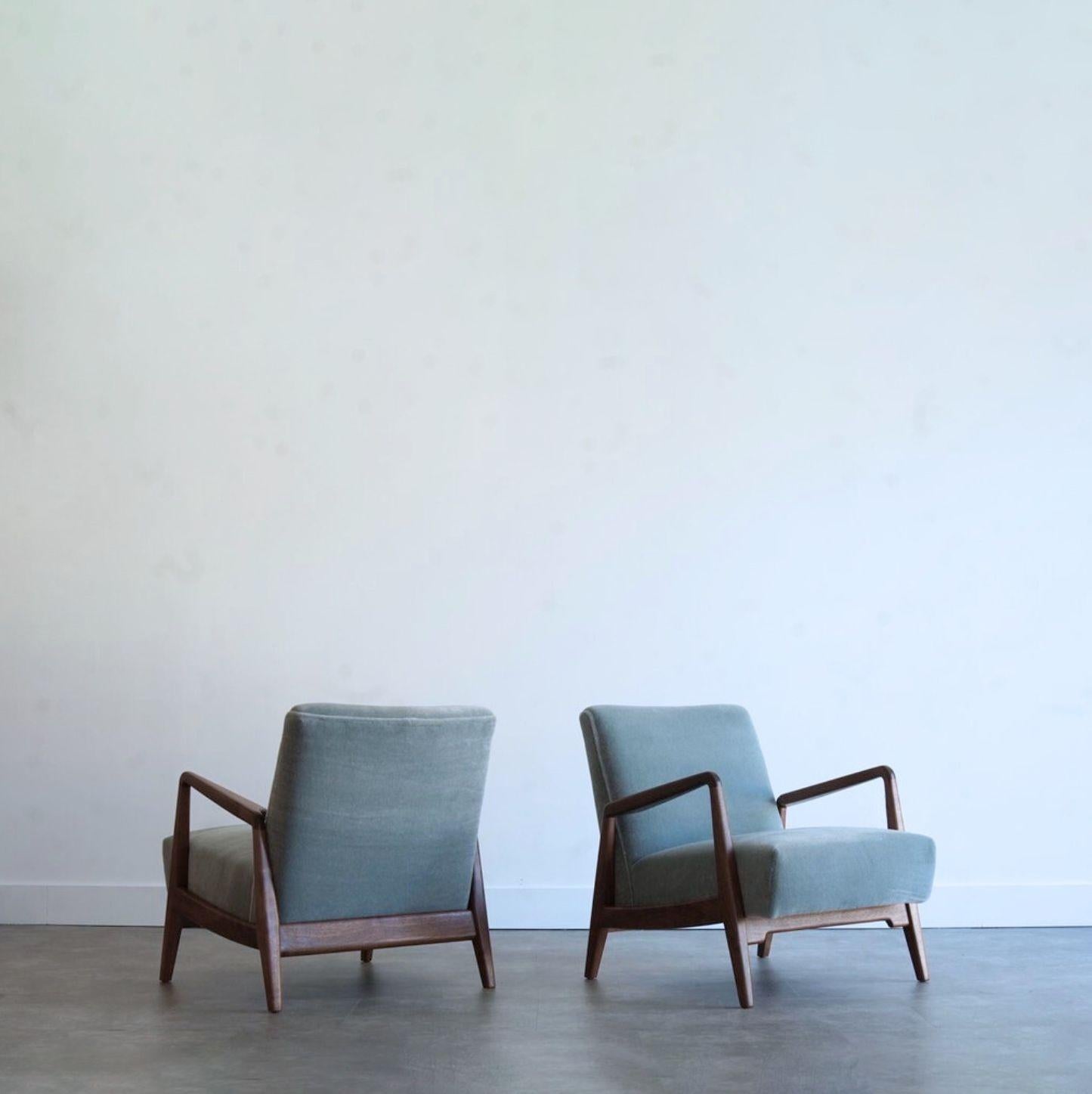 A stunning pair of walnut lounge chairs by Danish-American designer Jens Risom, circa 1950s. Expertly restored by Stamford Modern, the solid walnut frames feature a rich natural finish, highlighting their sculptural form. Reupholstered in luxurious