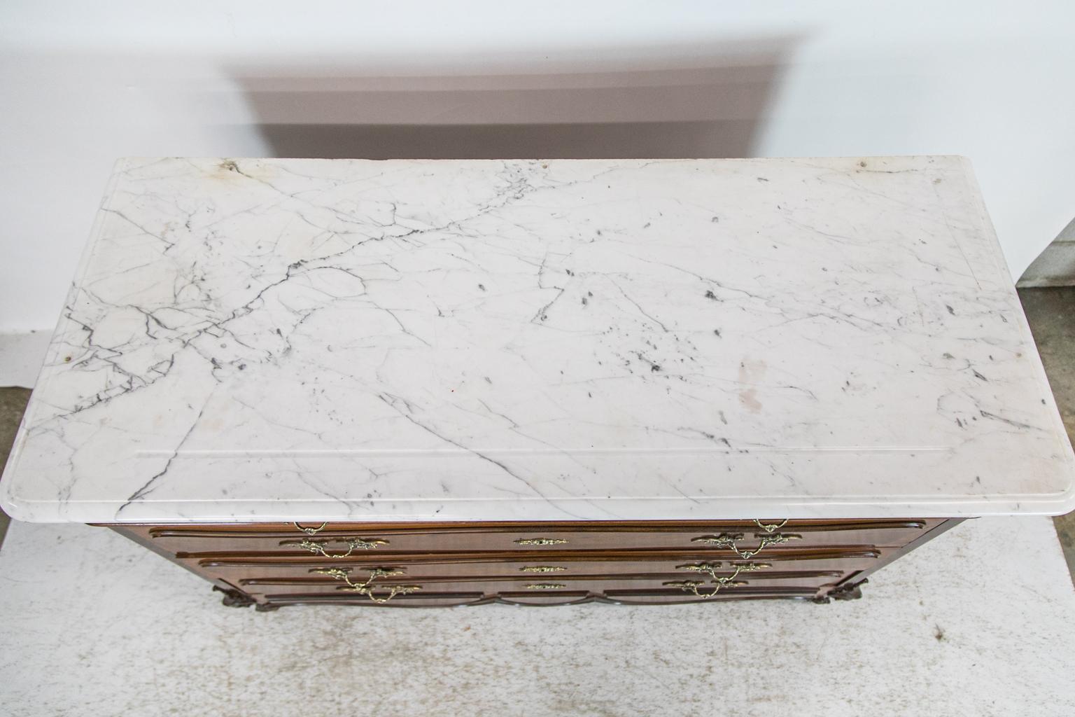 This chest has a Carrera marble with a shaped groove in the front. There are three holes on the back edge which have been filled. The drawer fronts have applied shaped raised panels in serpentine shapes. The sides have recessed panels. There is a