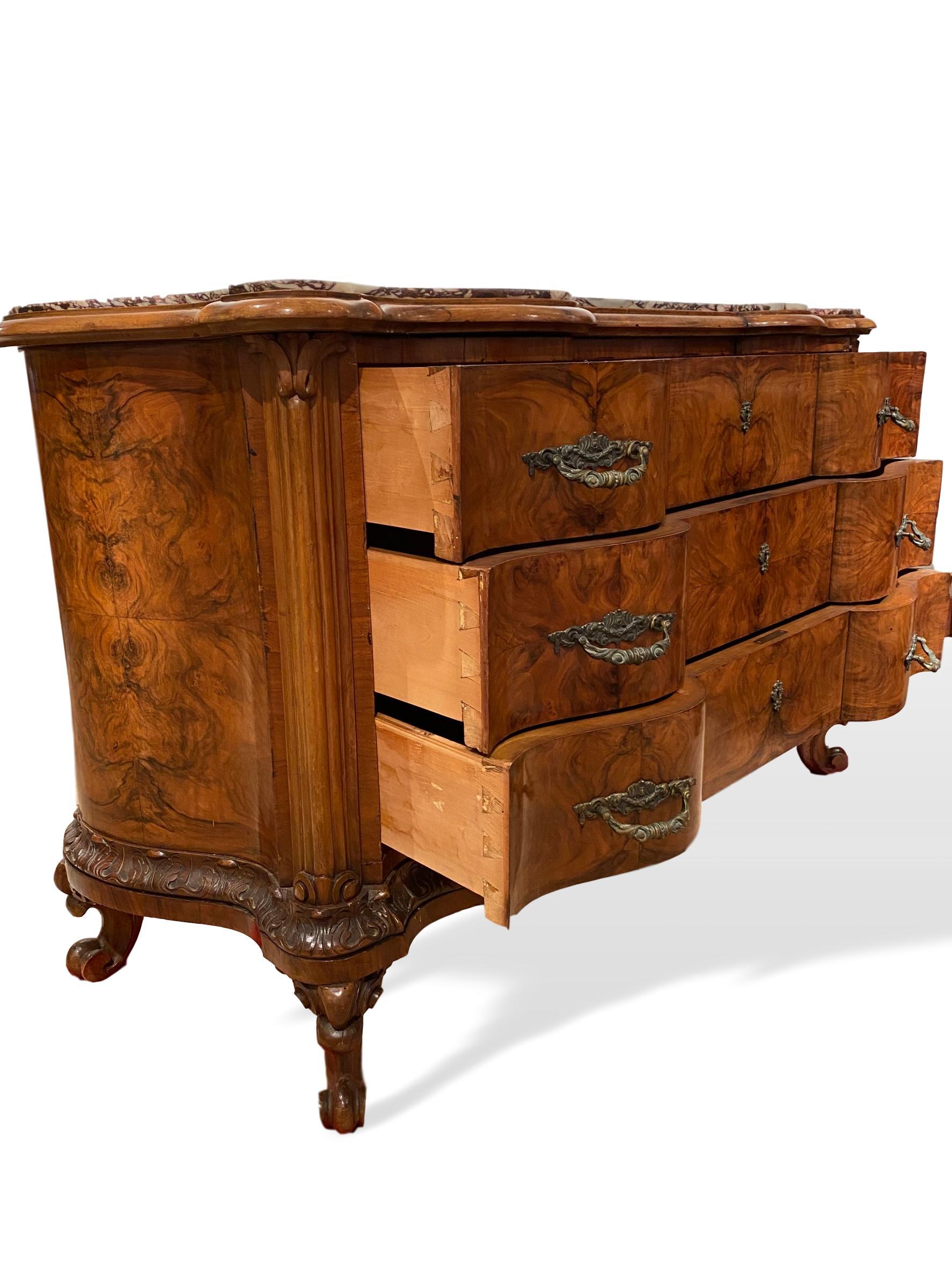Walnut marble-top serpentine commode, Italian, circa 1880, with shaped marble top over three serpentine drawers, above a foliate carved apron, on elaborately carved whorl feet--all hand carved. The piece retains all of its original gilt bronze