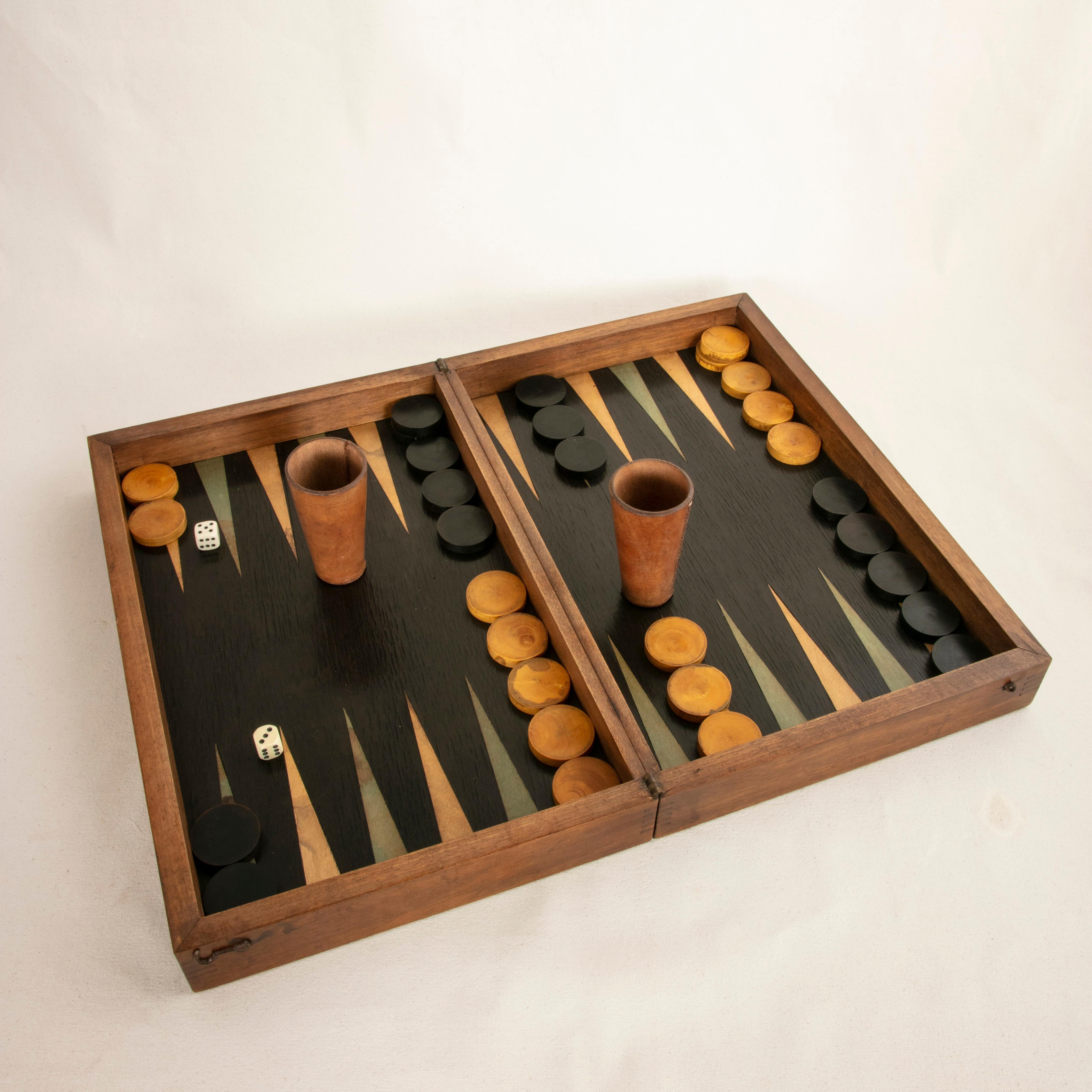 This French walnut marquetry folding game box from the turn of the 20th century is for checkers, chess, and backgammon. It is finely constructed with dovetailed corners, inset hinges, and a locking brass hook on each side. The checker board side of