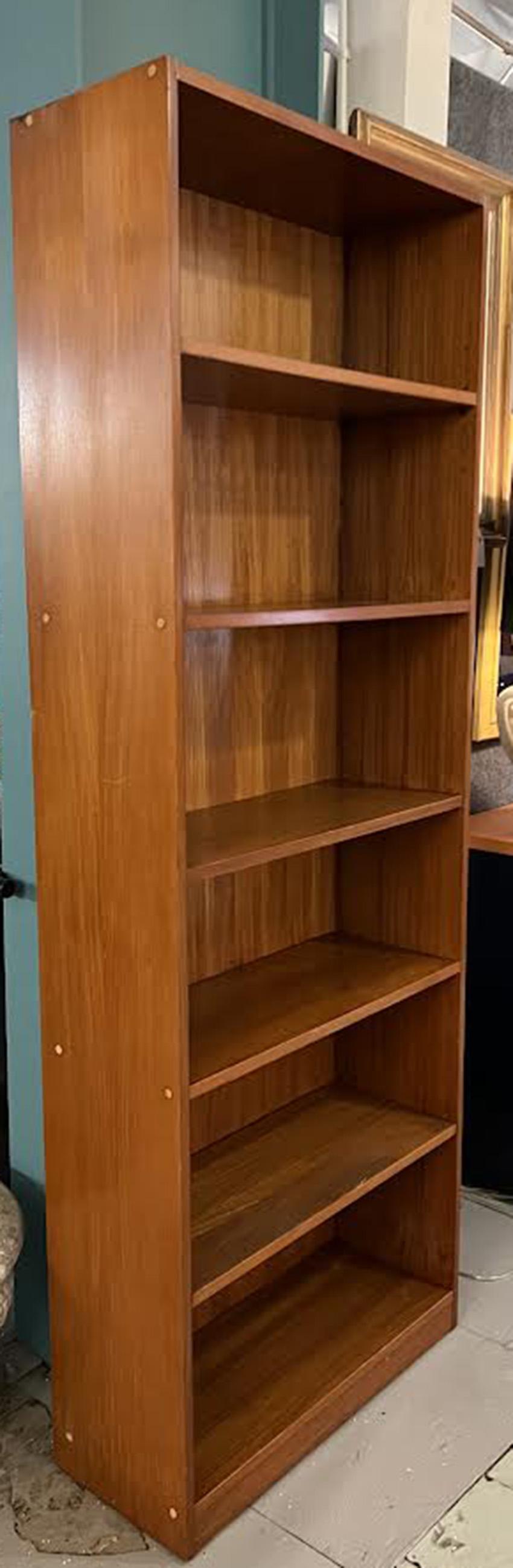 Dieses klassische, moderne Bücherregal aus der Mitte des Jahrhunderts ist aus blondem Walnussfurnier gefertigt und besticht durch sein zeitloses Design. Mit einer Höhe von 79 Zoll, einer Breite von 29,5 Zoll und einer Tiefe von 11,5 Zoll ist er eine