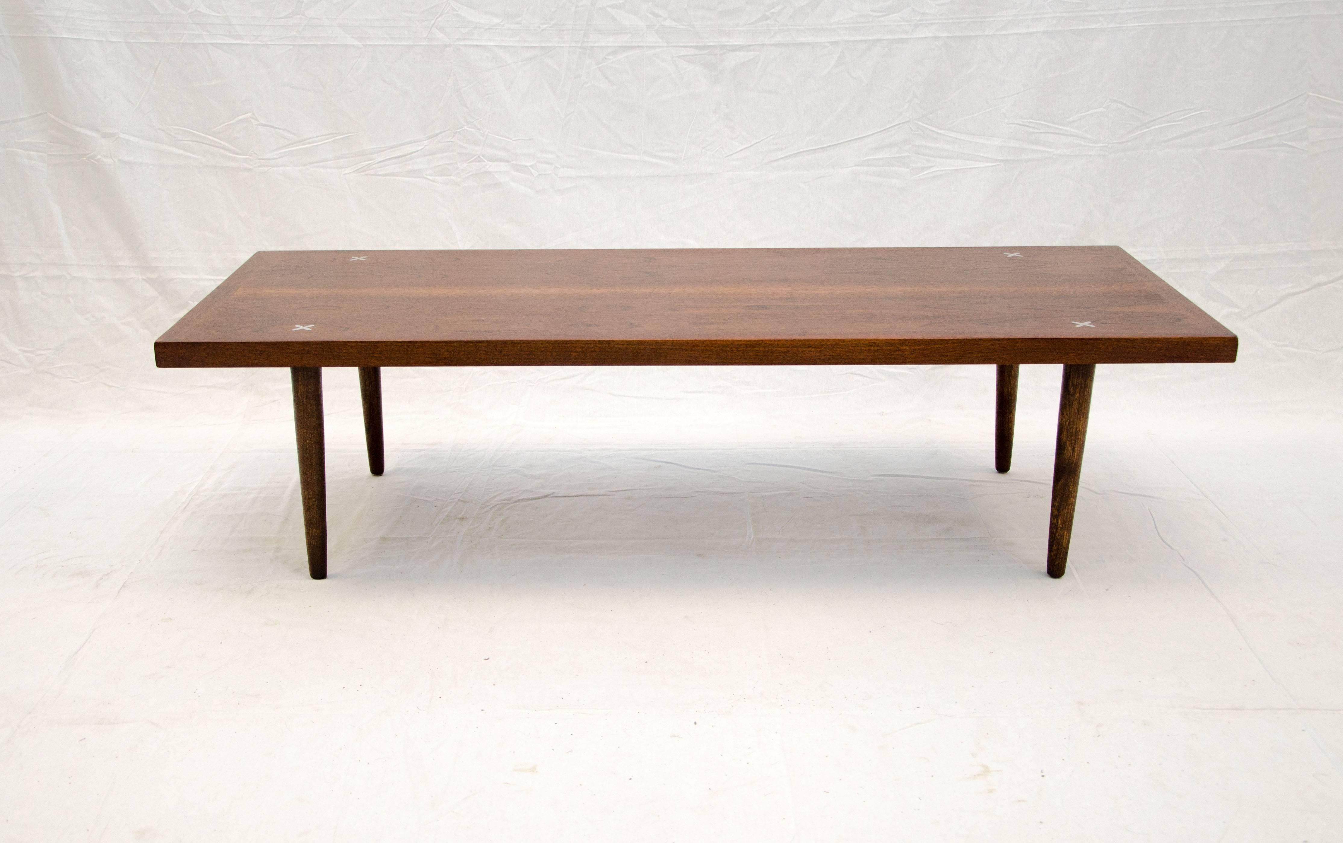 Nice medium size mid century coffee or cocktail table with the iconic American of Martinsville aluminum crosses inlaid on the corners. The table rises on round tapered legs.