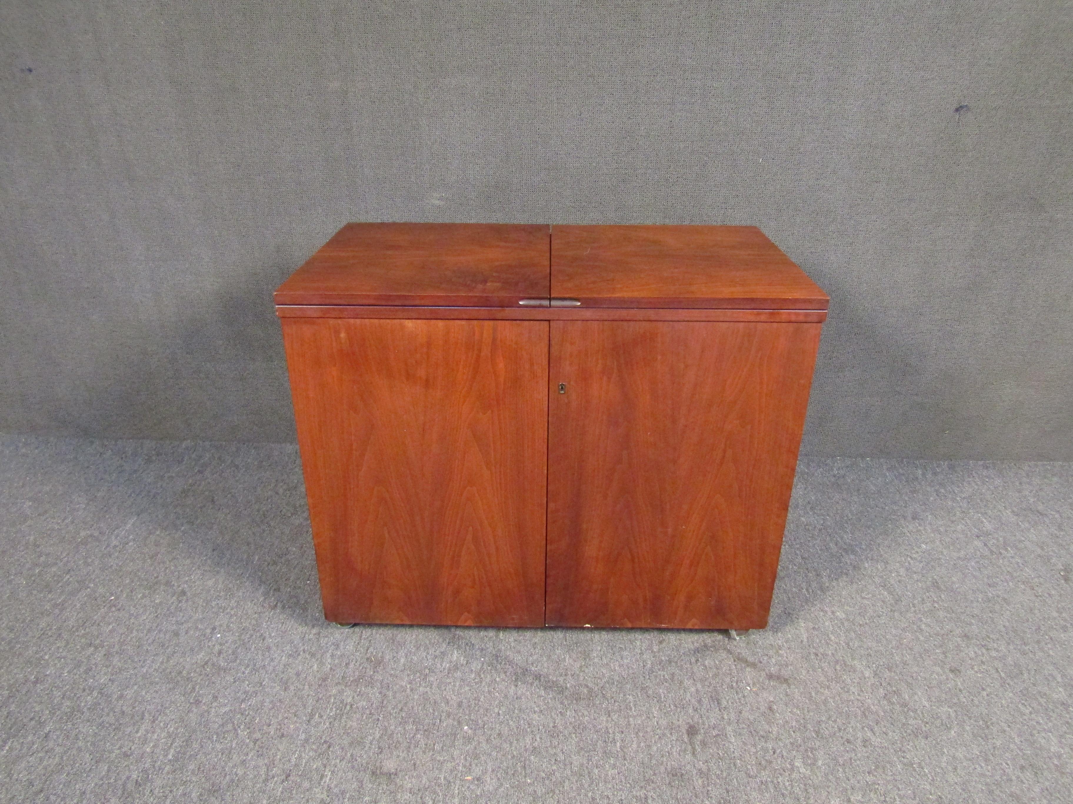 With a minimal and compact design, this vintage bar offers an impressive amount of storage for its size. Quality Mid-Century craftsmanship and rich walnut make this piece beautiful and functional. Please confirm item location with seller (NY/NJ).