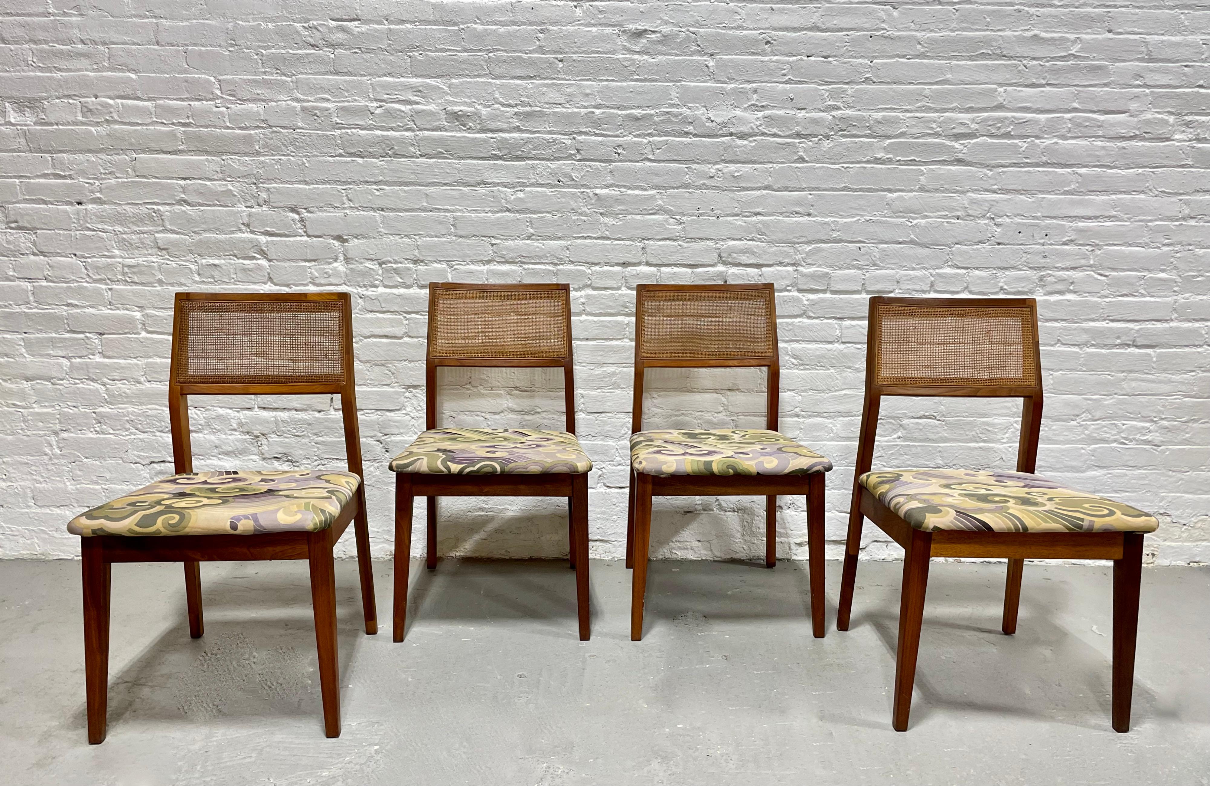 Set of four Mid Century Modern Walnut Caned dining chairs, c. 1960's. Lovely solid frames with incredible wood coloring and perfectly caned back rests. Upholstery is a vibrant retro fabric in nice condition (some light stains on fabric but