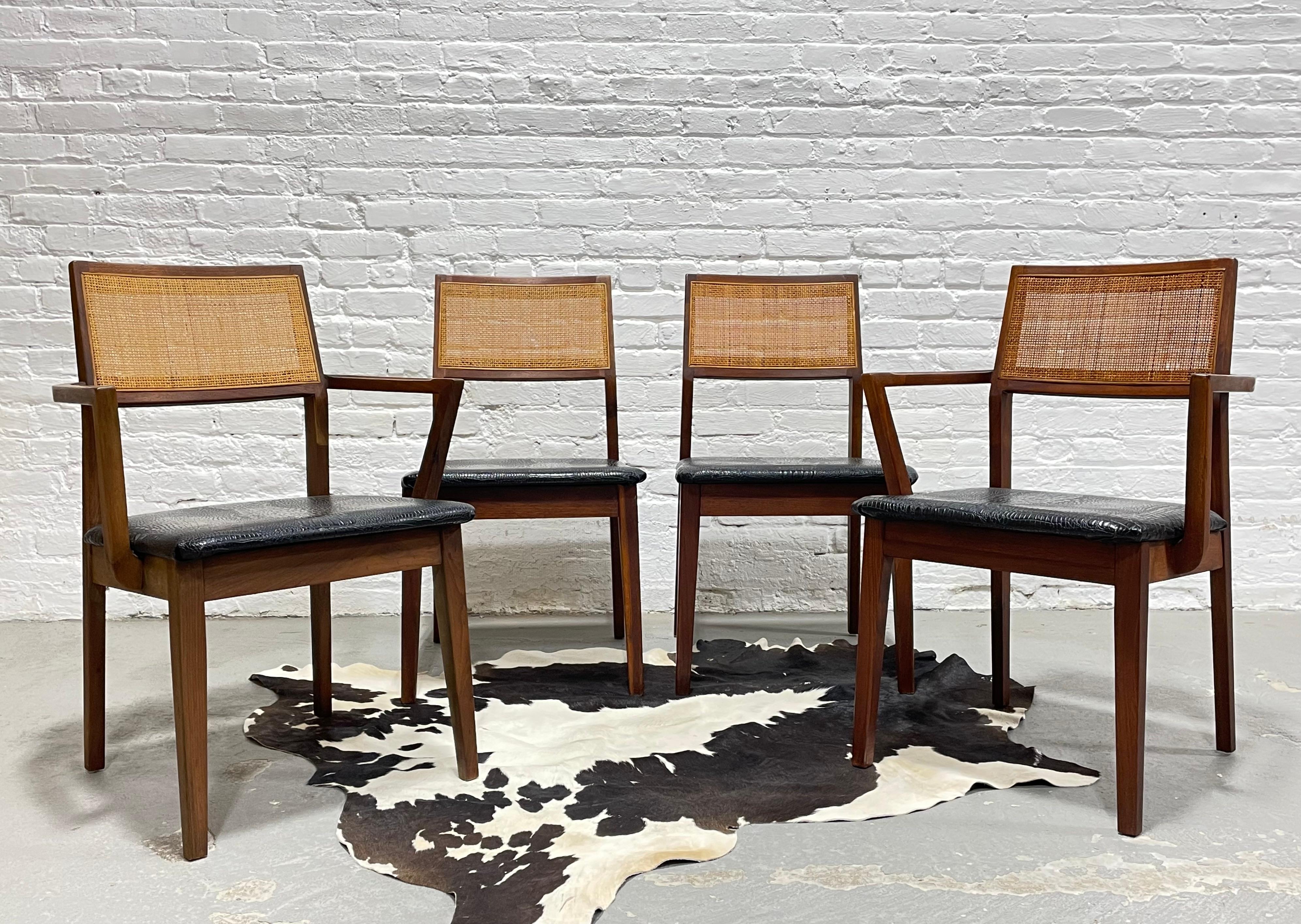 Set of four Mid Century Modern Walnut Caned Dining Chairs, c. 1960's. Lovely solid frames with incredible wood coloring and caned back rests. Upholstery is a black naugahyde which easily matches with everything and is in nice condition. A few small