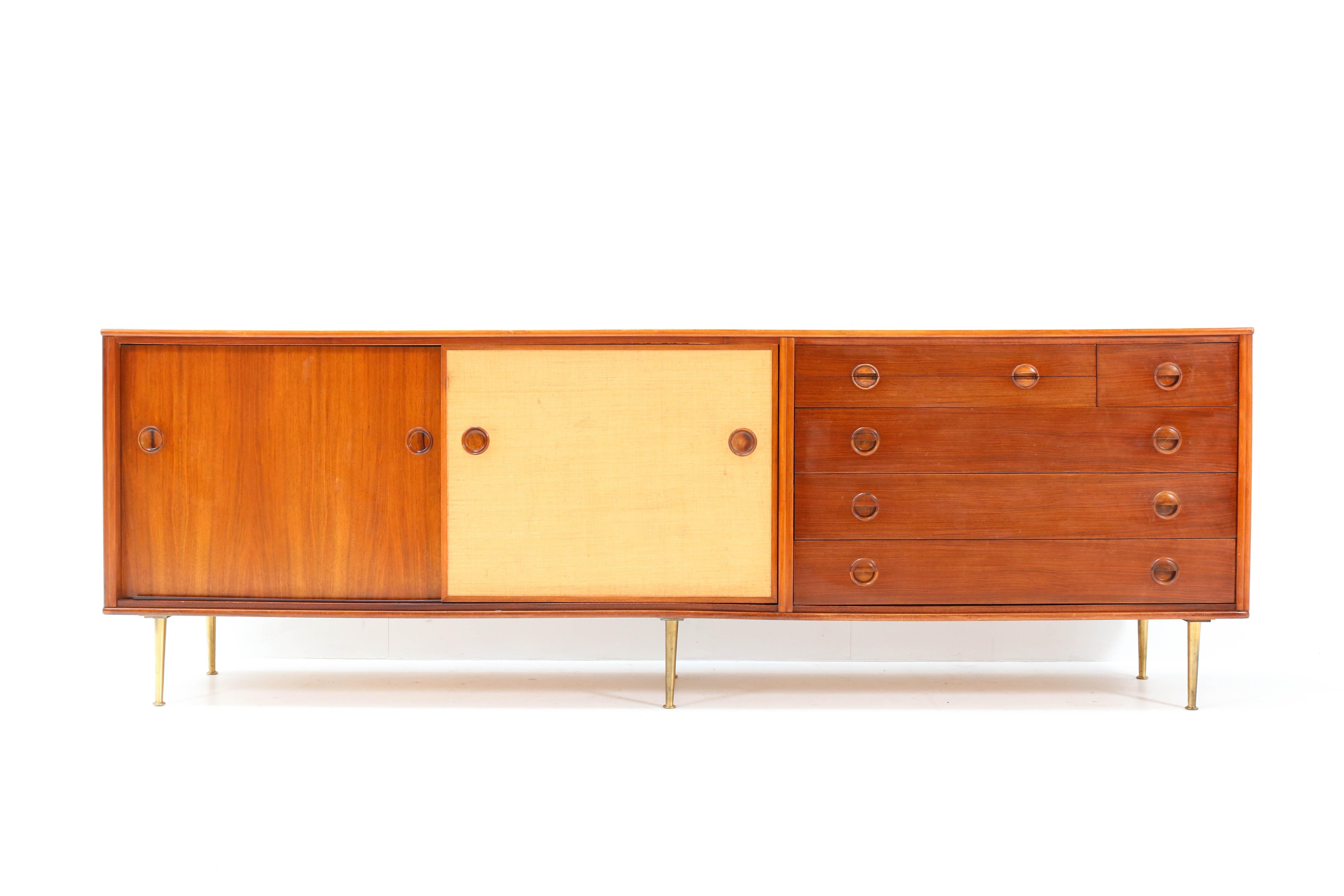 Magnificent and rare Mid-Century Modern credenza or sideboard.
Design by William Watting for Fristho Franeker.
Striking Dutch design from the 1950s.
Solid walnut and solid walnut veneer on brass legs.
One of the two sliding doors is upholstered