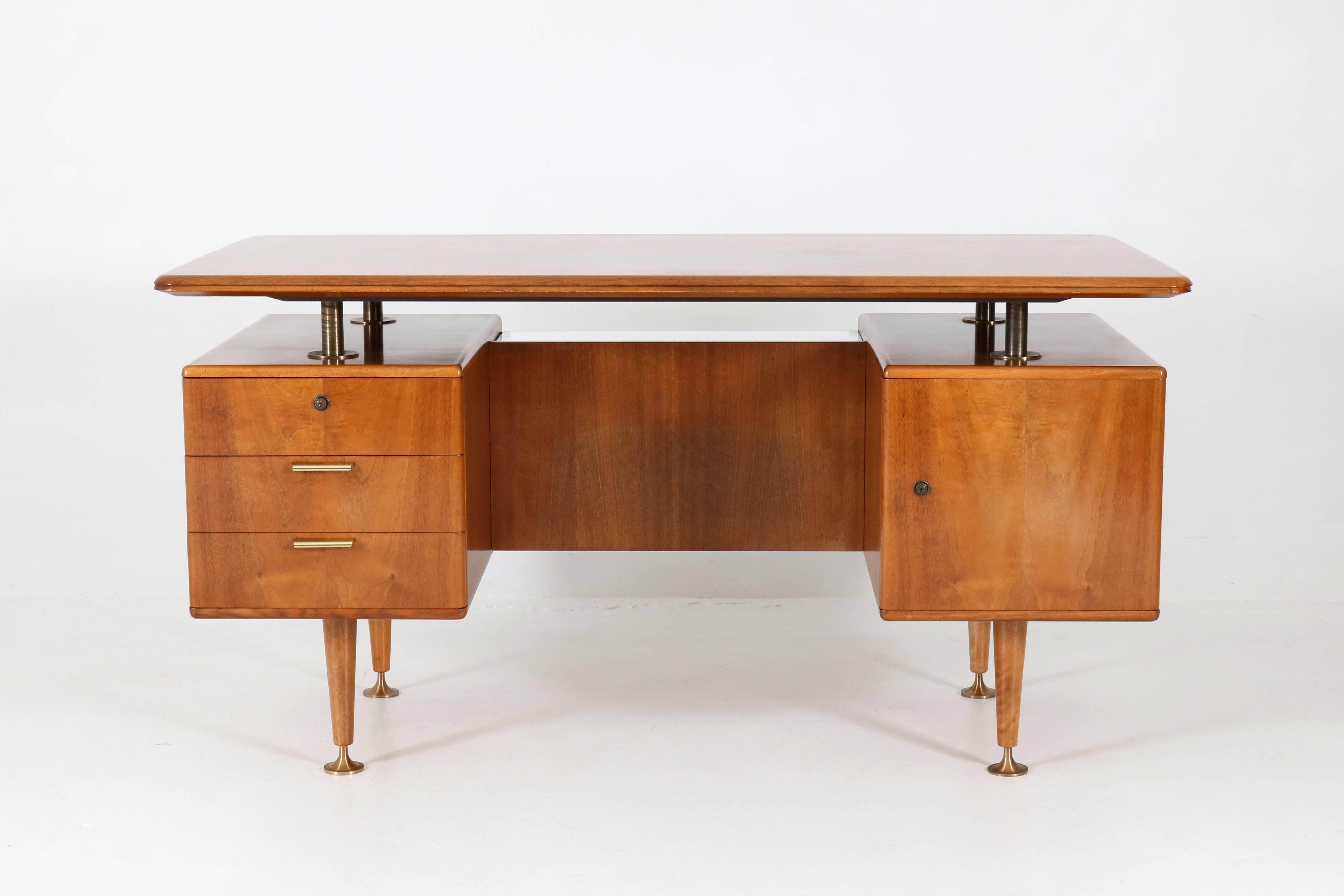 Elegant Mid-Century Modern floating top desk by A.A.Patijn for Poly-Z.
Striking Dutch design from the 1960s.
Walnut with solid brass handles and feet.
Two original glass shelves at the back of the desk.

On the top there is a darker spot