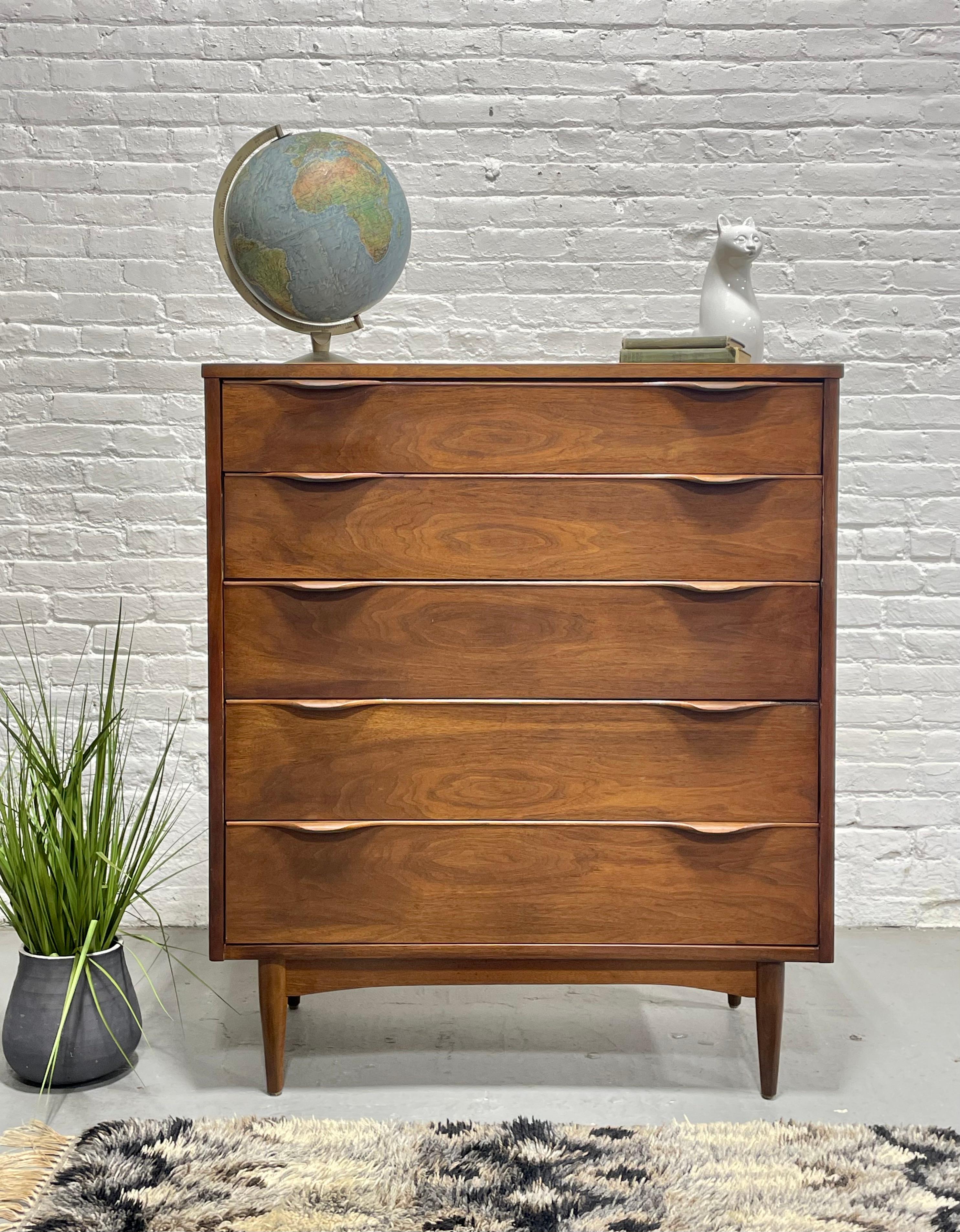 Mid Century Modern Walnut Tall Dresser / Highboy featuring gorgeous sculpted hand-pulls, c. 1960's.  The five deep and spacious drawers offer a wealth of storage and the wood grains are stunning throughout this well-made dresser. The tabletop is a
