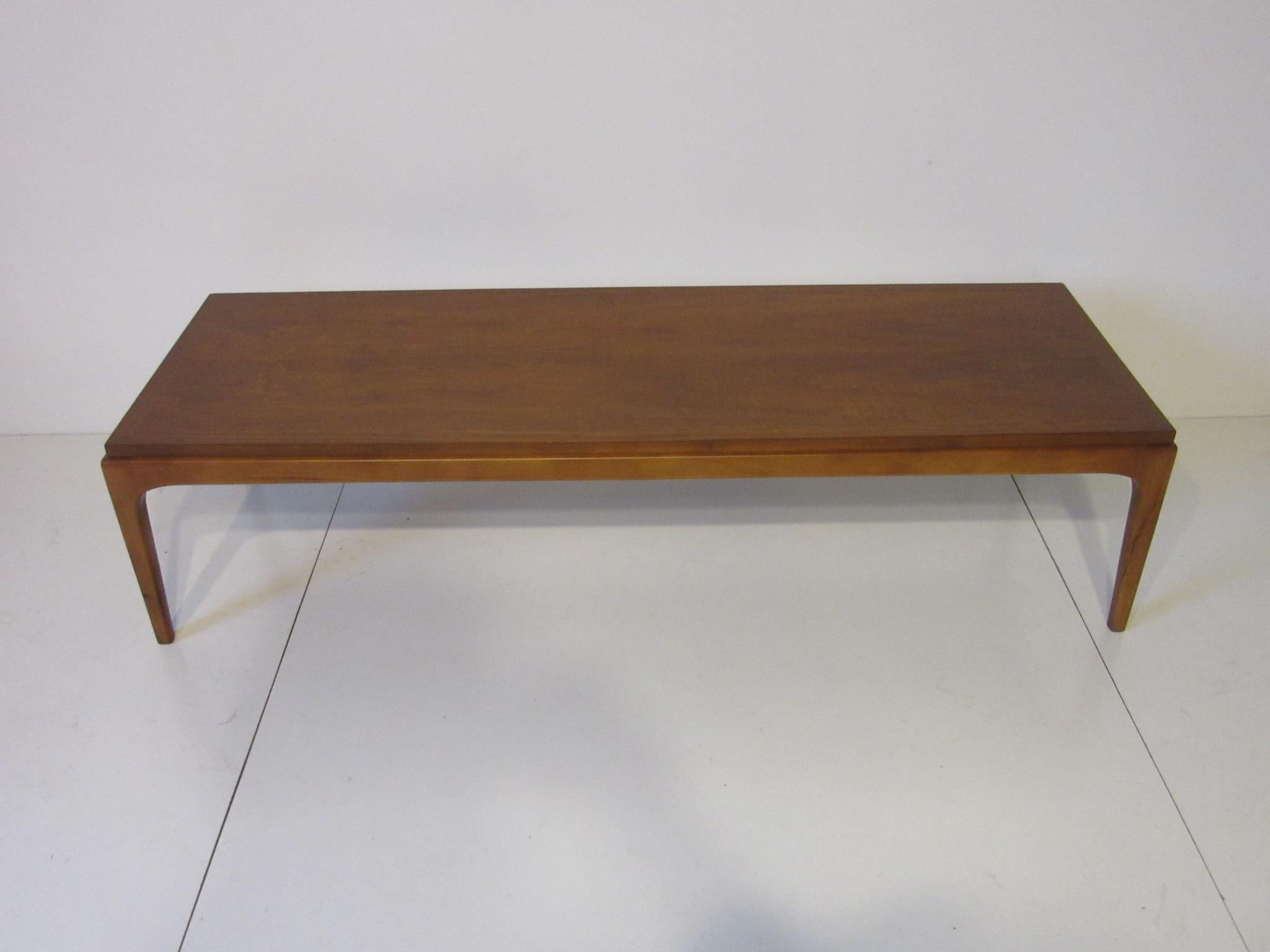 A medium toned walnut midcentury coffee table with a nice thin profile and solid construction, manufactured by Lane Altavista.
