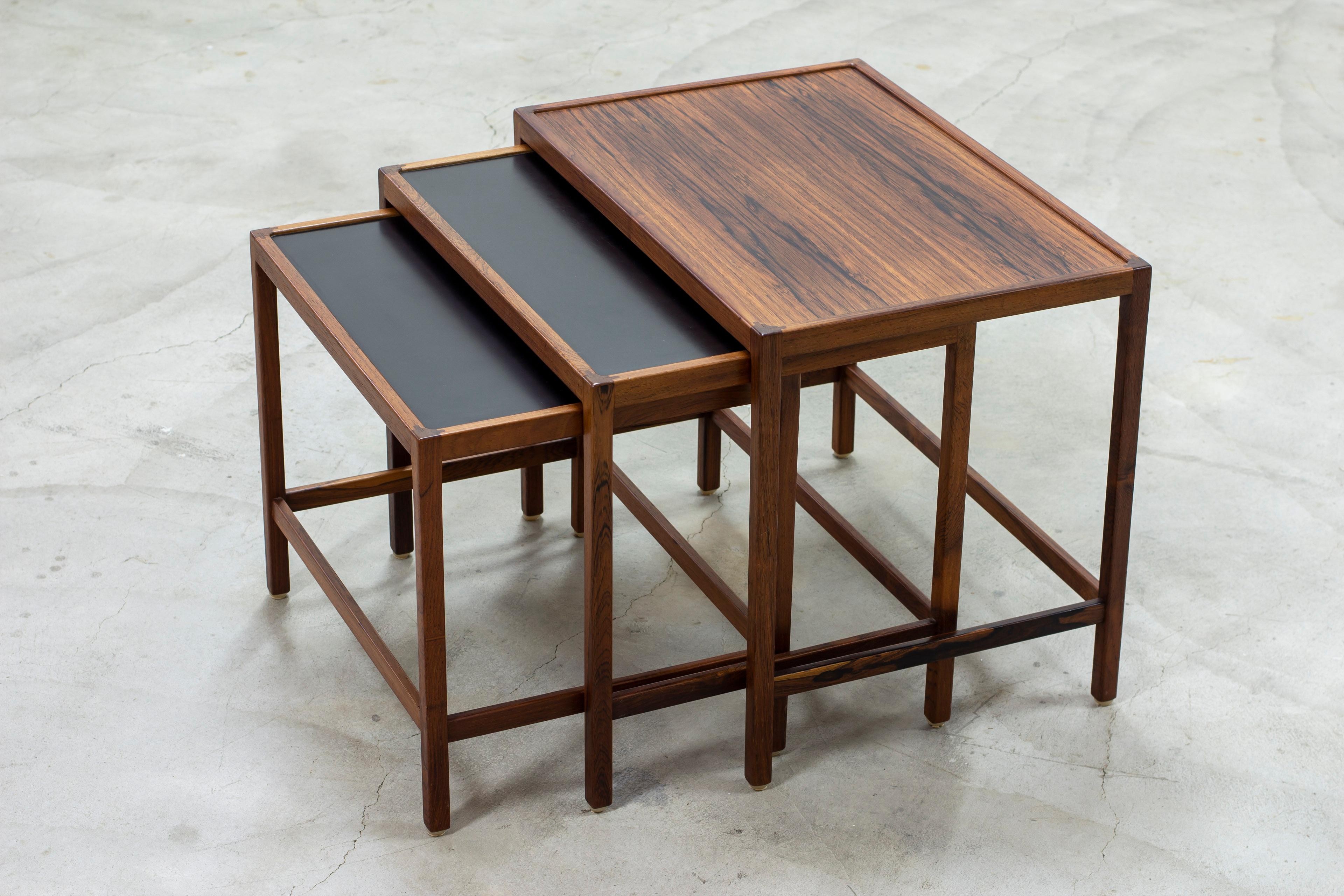 Nesting table model 100 designed by Kurt Østervig. Produced in Denmark by Jason Møbler during the 1950-60s. Made from solid rosewood with nice details as exposed joinery on the table top edge and black formica table tops on the two smaller tables.