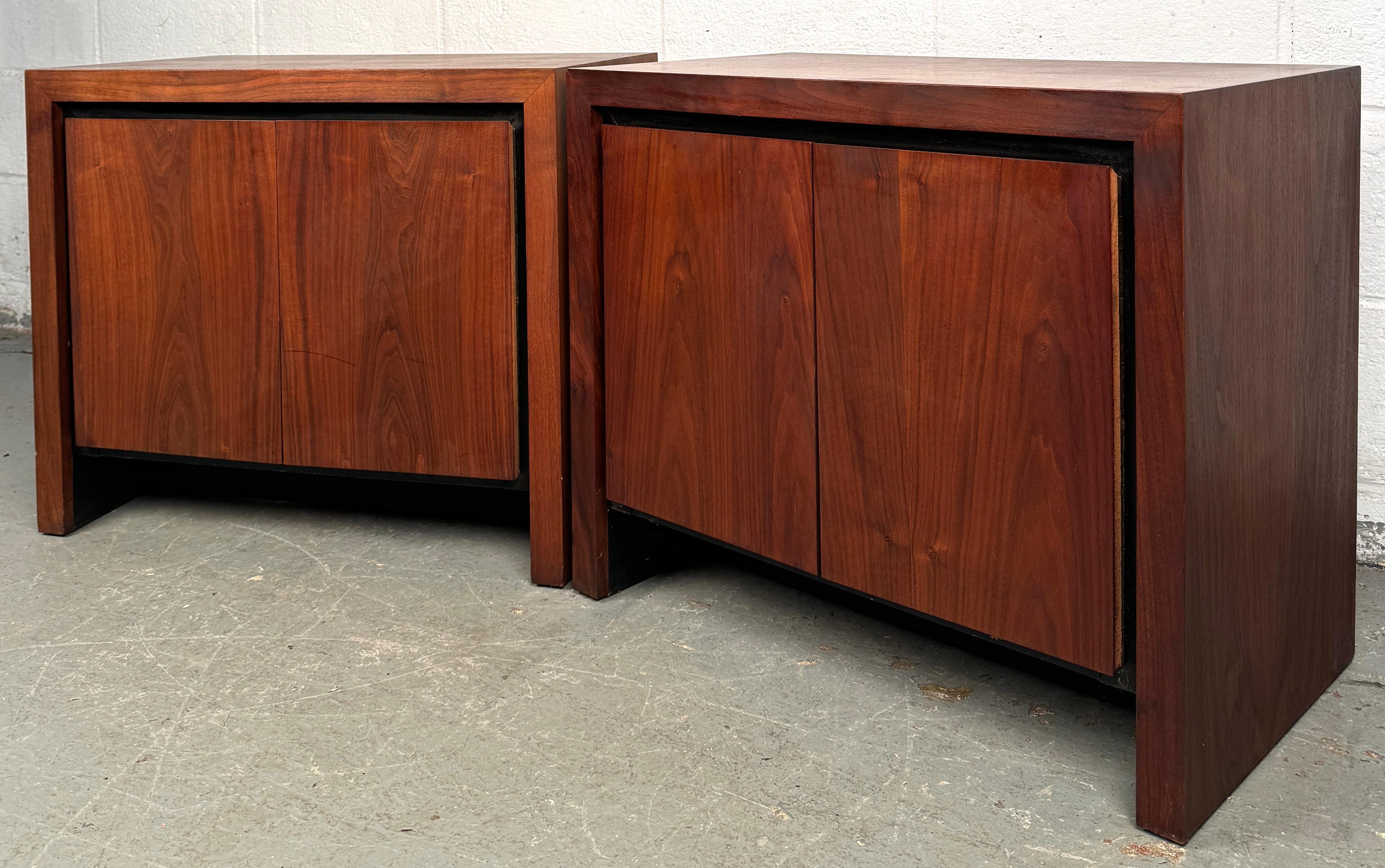 Une paire classique de tables de nuit en noyer du milieu du siècle, avec des tons de bois chauds, des lignes épurées et un design intemporel. Chaque meuble offre un rangement pratique avec un ou plusieurs tiroirs et repose sur des pieds fuselés,