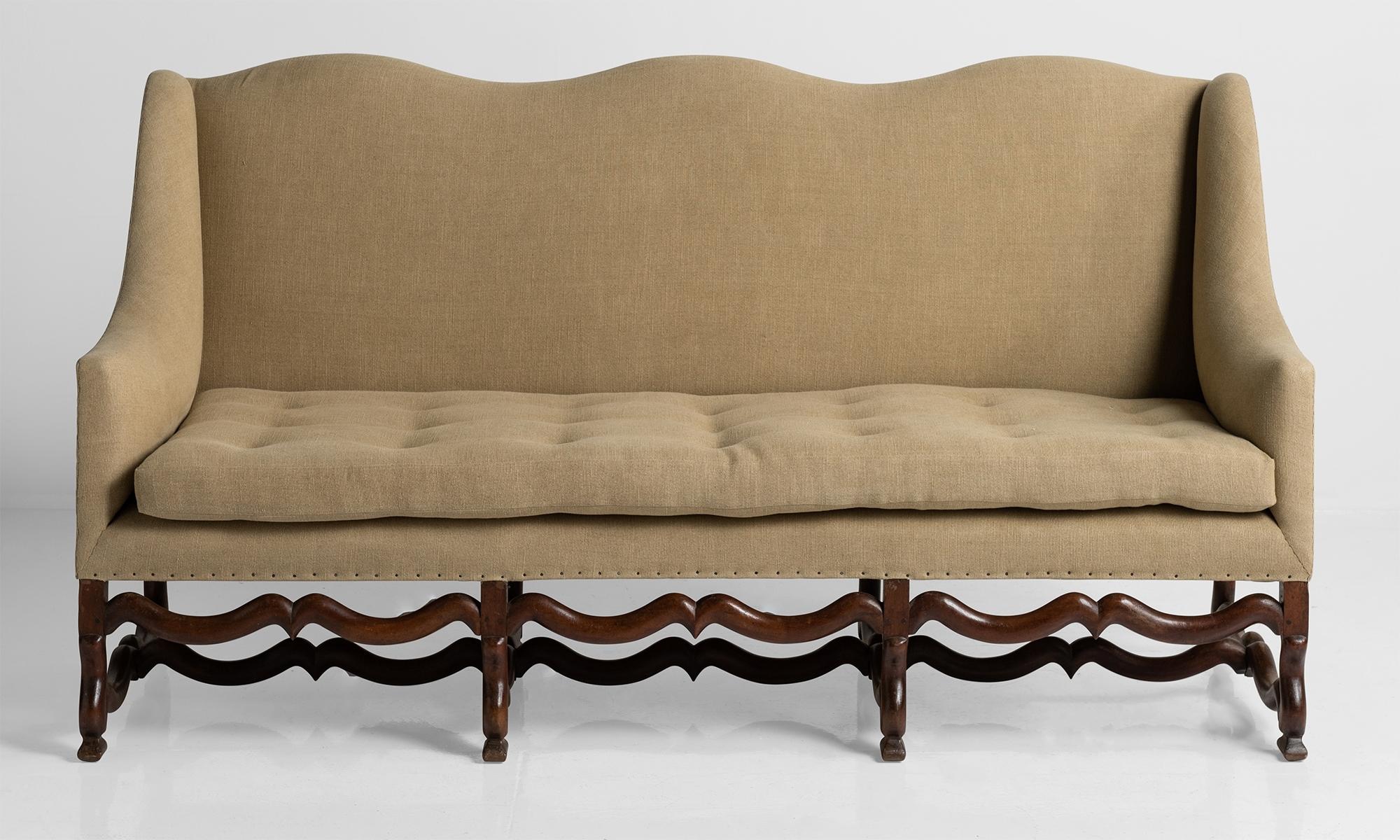 Deeply seated sofa with wavy top rail and box wing sides on Os de Mouton frame.