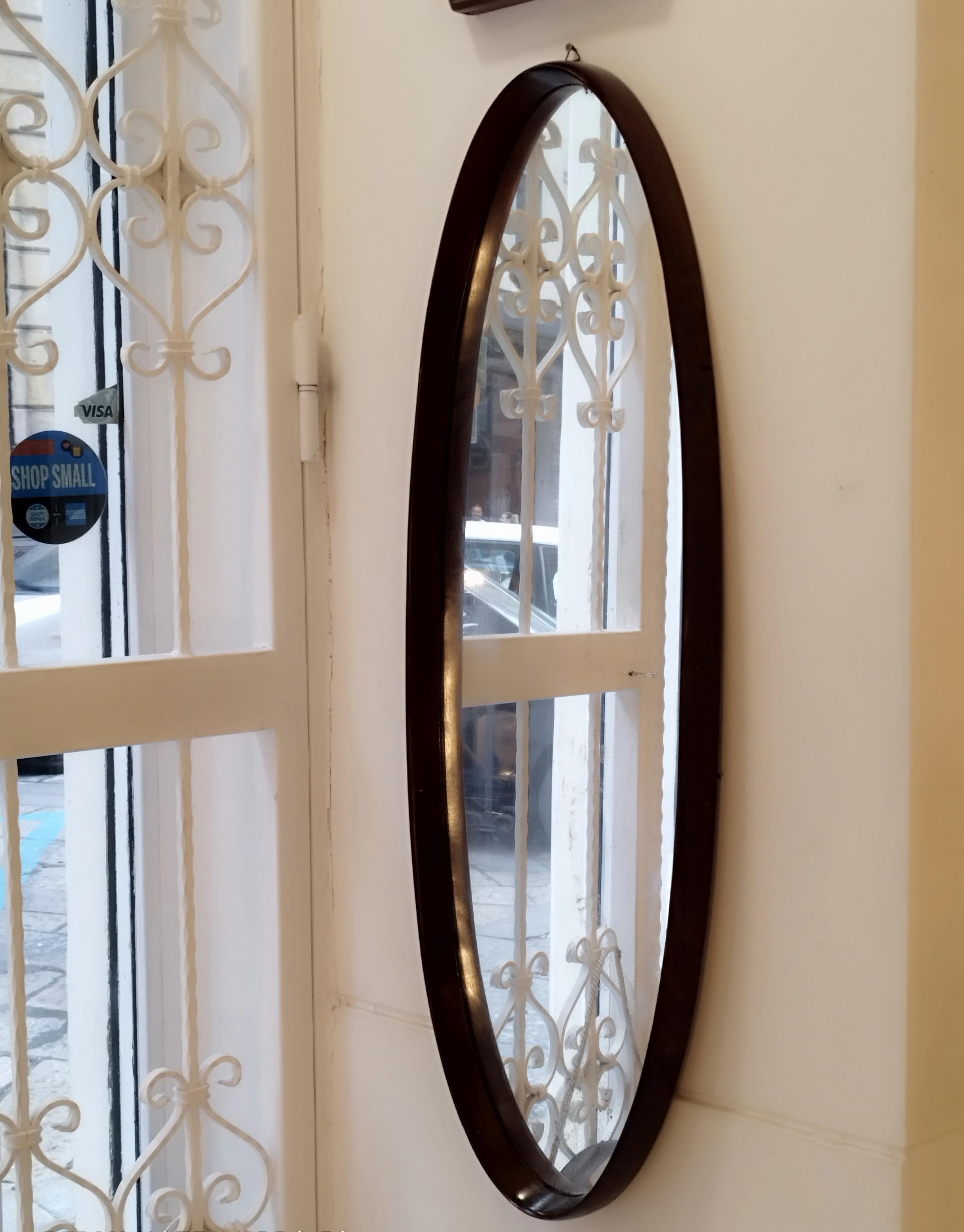 Large oval mirror with curved wooden frame, made in Italy in the 1960s. Wooden back panel.
Good overall condition, some marks due to normal use over time.