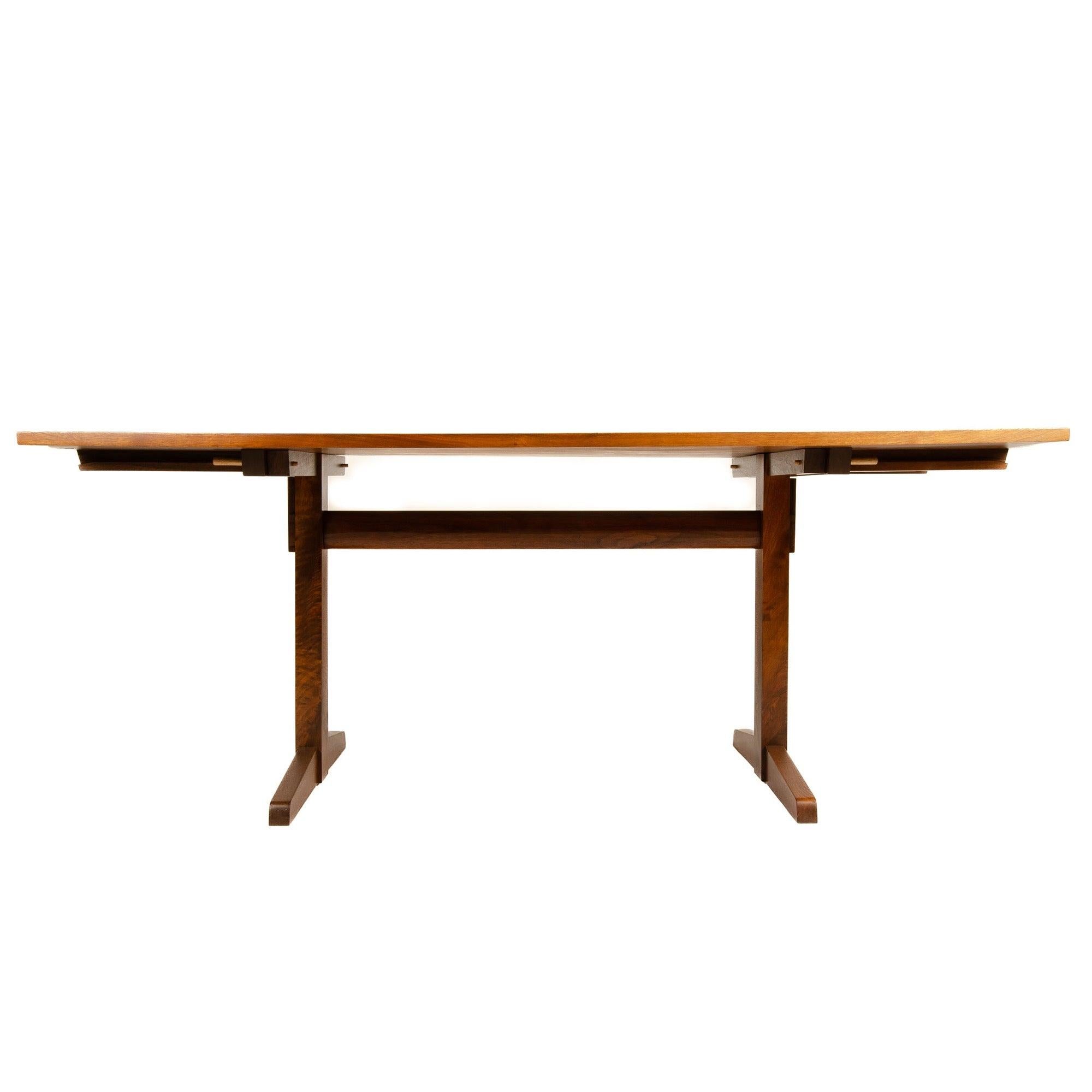 A fine, solid walnut plank top trestle table with an exposed tenon key stretcher, pegged shoe feet, total length includes two 14