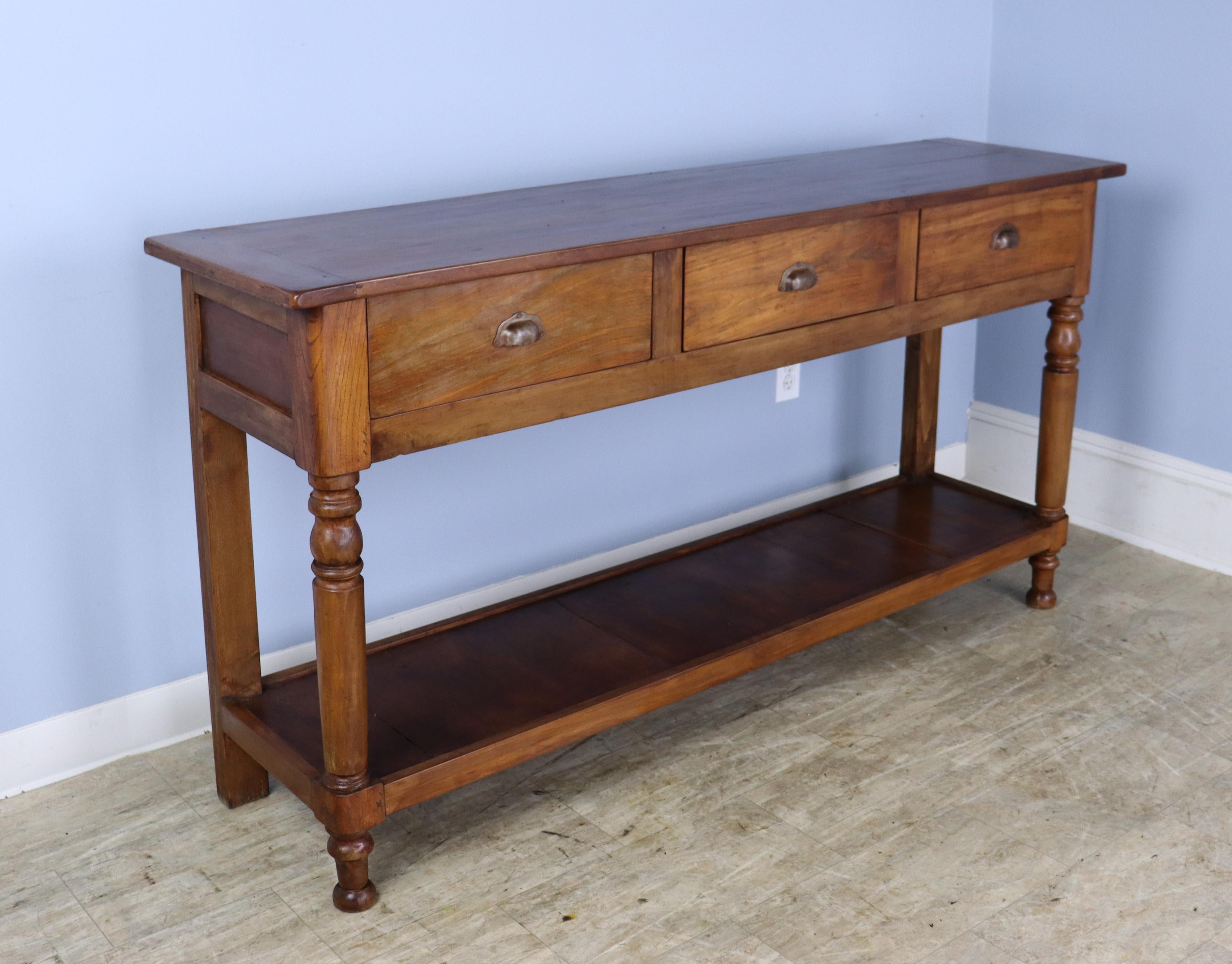 A lovely walnut potboard server, custom made for Briggs House in France with old legs, circa 1850. Generously proportioned with a thick top, three roomy drawers, and vivid walnut color. There is some distress on the old wood used in making the
