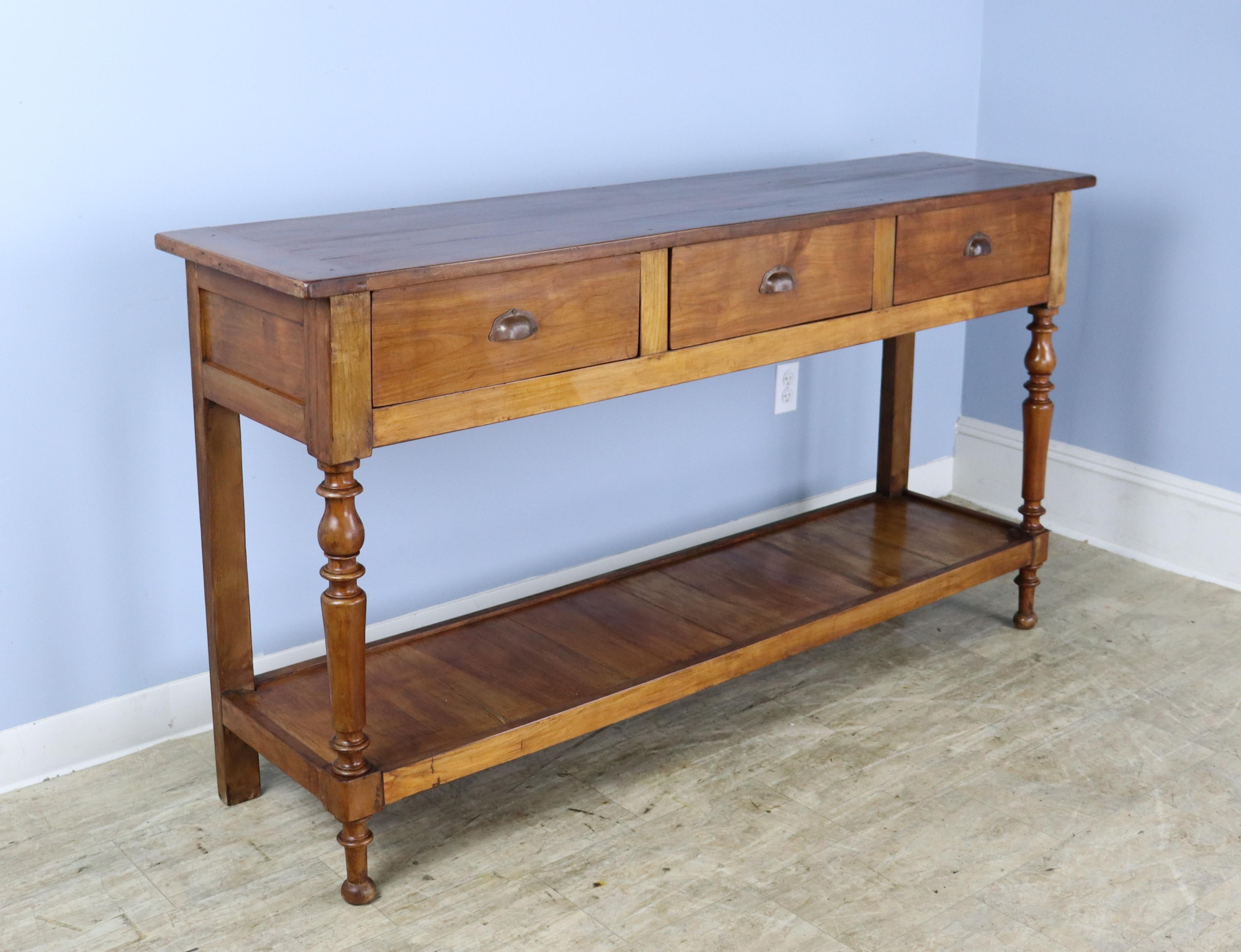 A lovely walnut potboard server, custom made for Briggs House in France with old legs, circa 1850. Generously proportioned with a thick top, three roomy drawers, and vivid walnut color. There is some light distress on the old wood used in making the