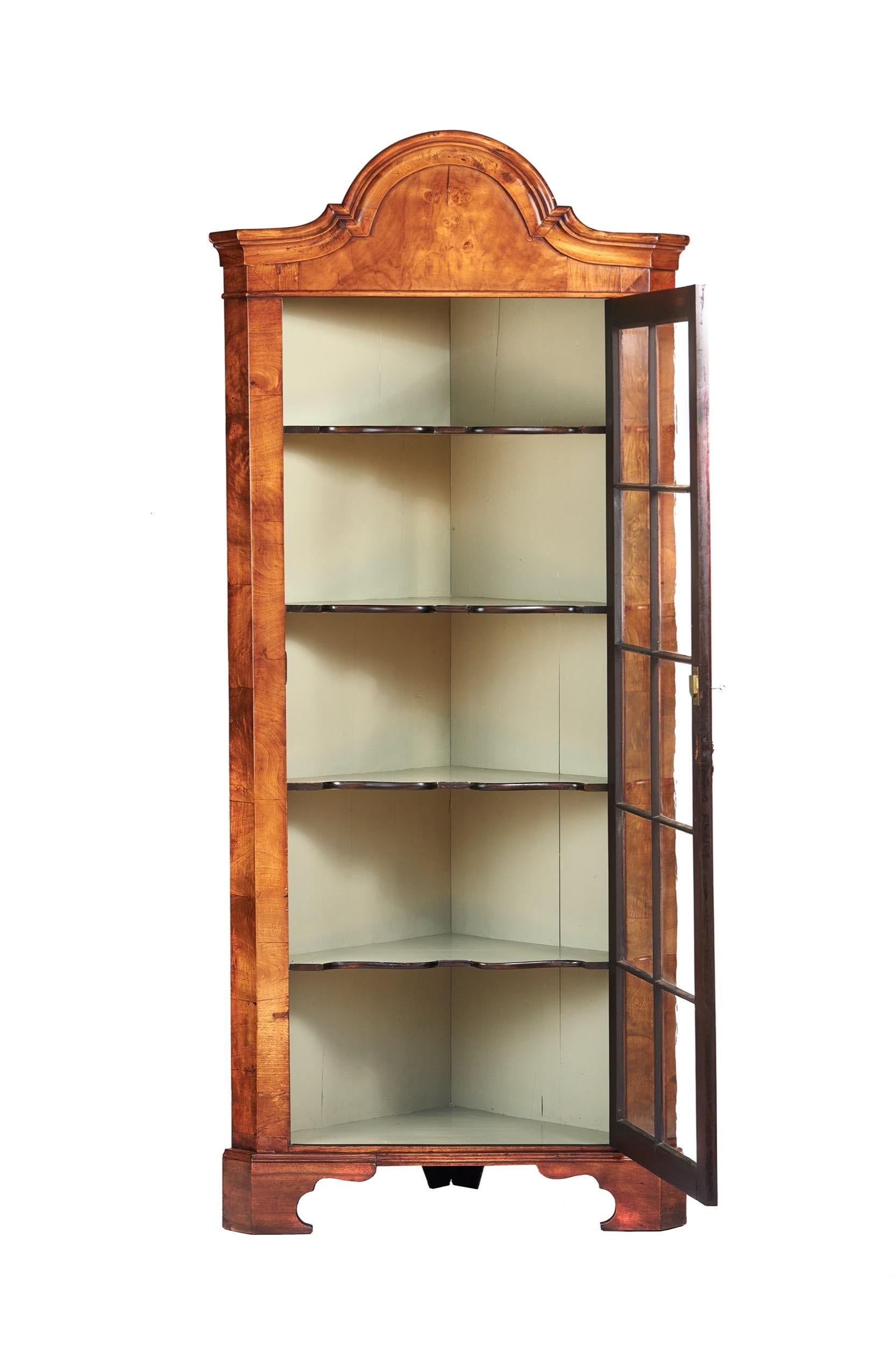 Walnut Queen Anne Revival floor standing Corner cabinet circa 1920s
Arch Shaped moulding on top,
Single Astragal Glazed door with Walnut Mould Bars,
Brass drop handle, with working lock & key, 
Open to Reveal 4 Fixed shelves, 
Painted Interior,