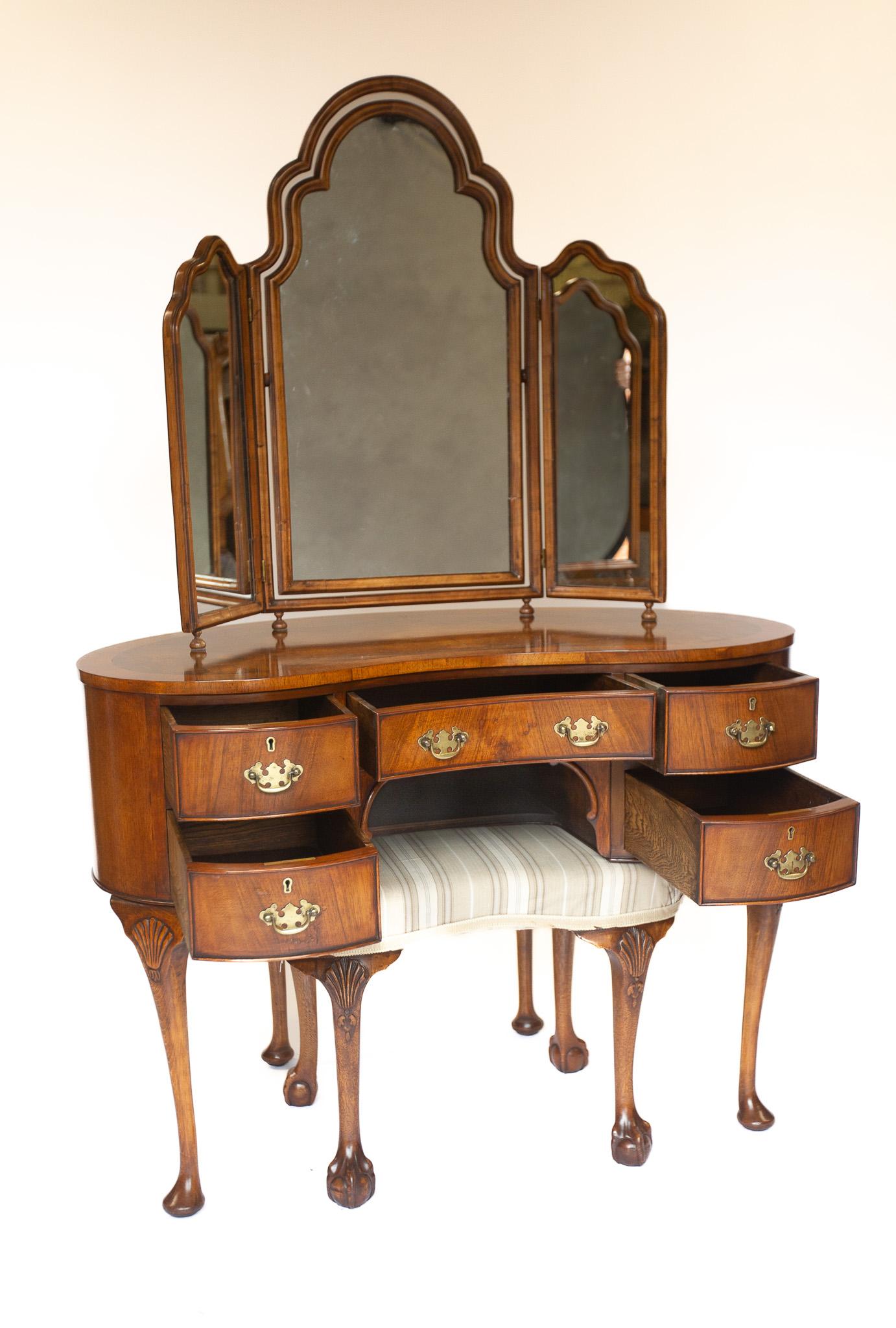 Table de toilette en noyer de style Queen Anne en forme de rein, années 1930
Dessus en noyer figuré, avec bandes transversales en noyer, 
Socle à 5 tiroirs à genouillère, avec poignées en laiton.
Elle repose sur quatre pieds en forme de cabriole,